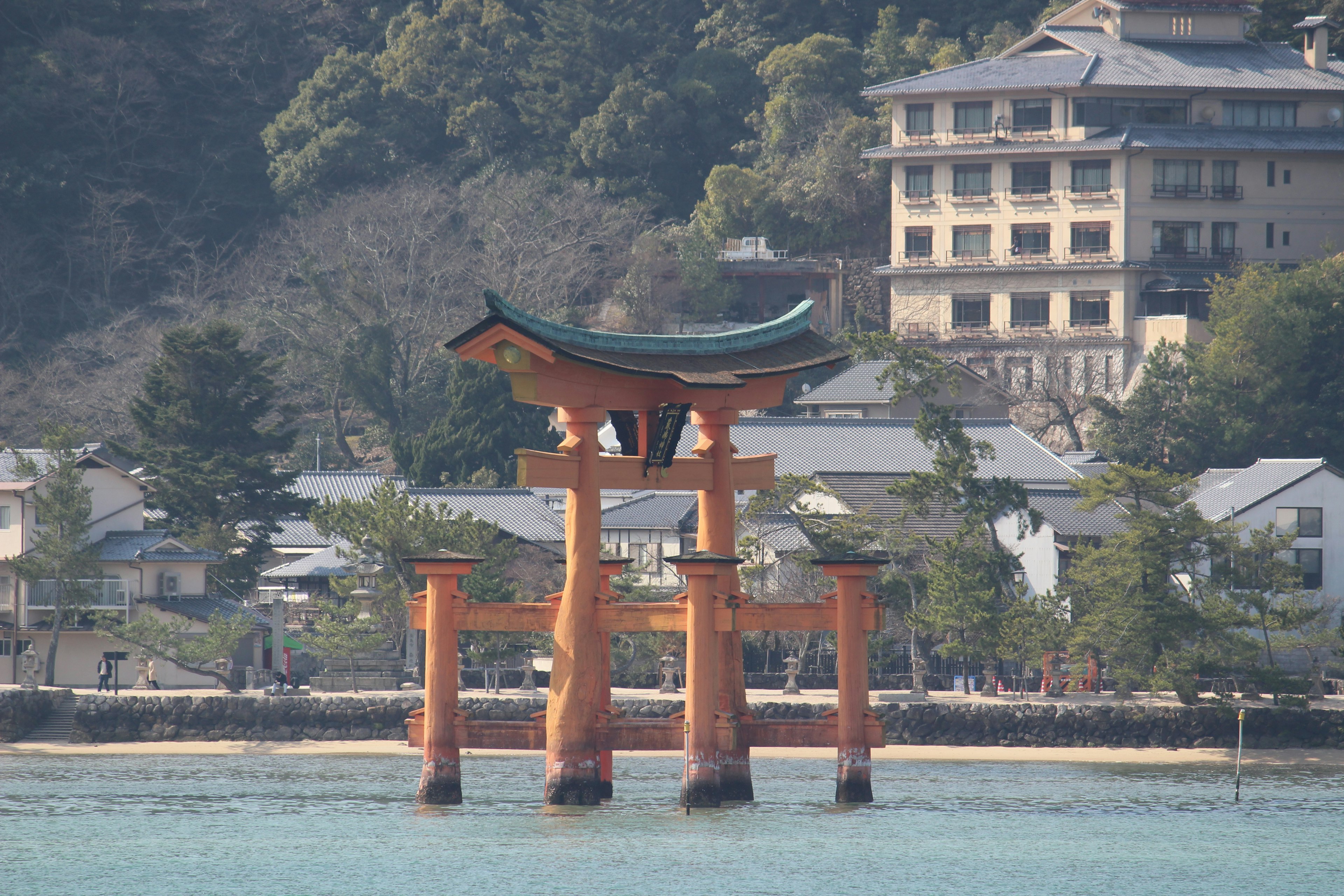 Puerta torii roja en el mar con montañas verdes de fondo