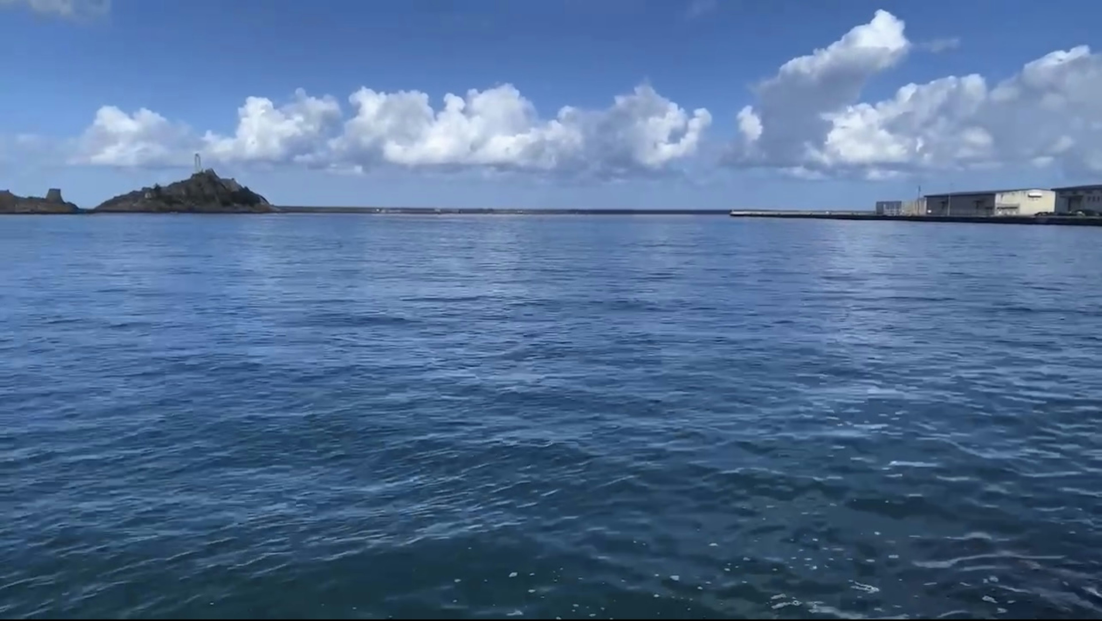 Mar tranquilo y cielo azul con vista a una isla y un puerto