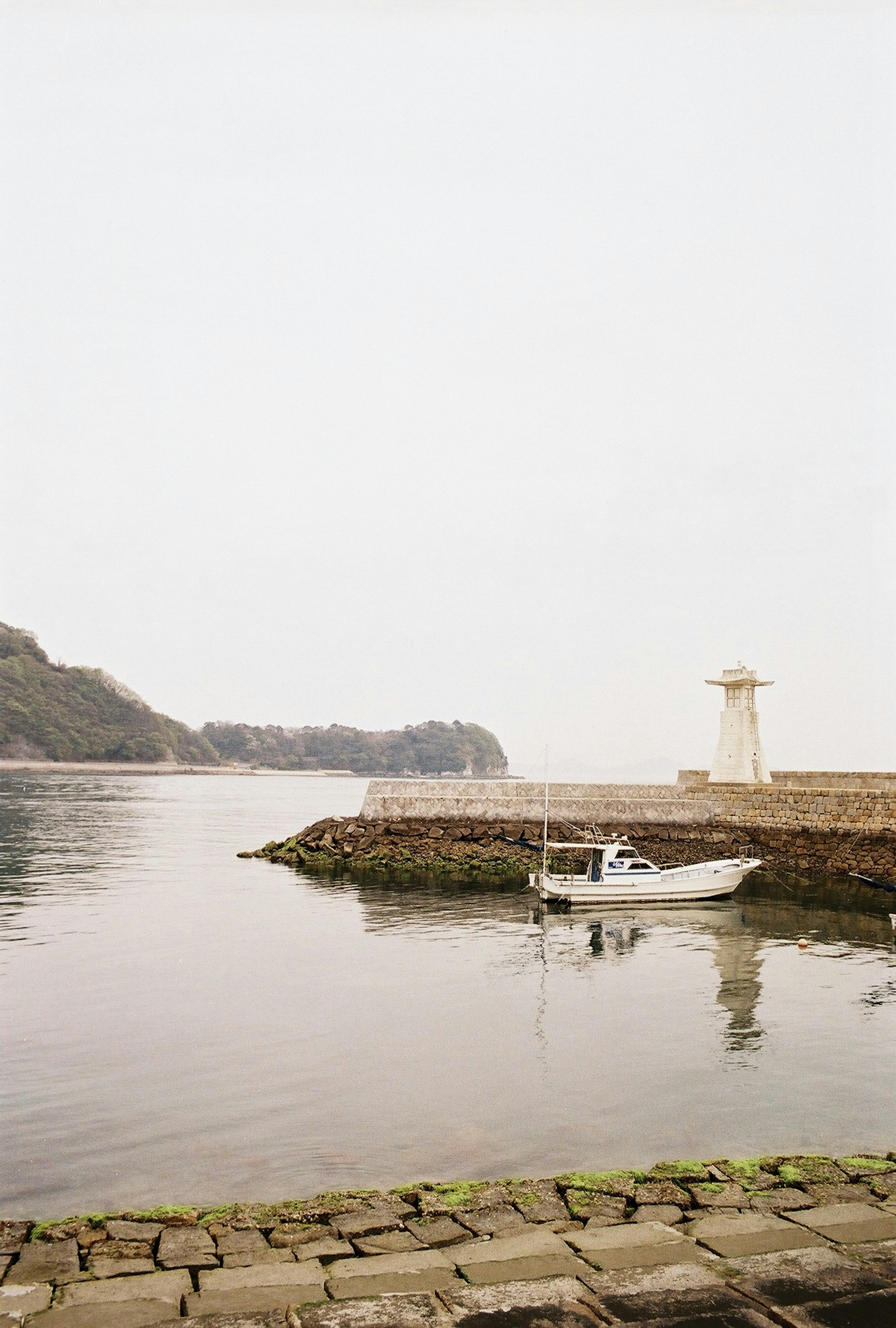 Calm harbor scene small boat and lighthouse visible