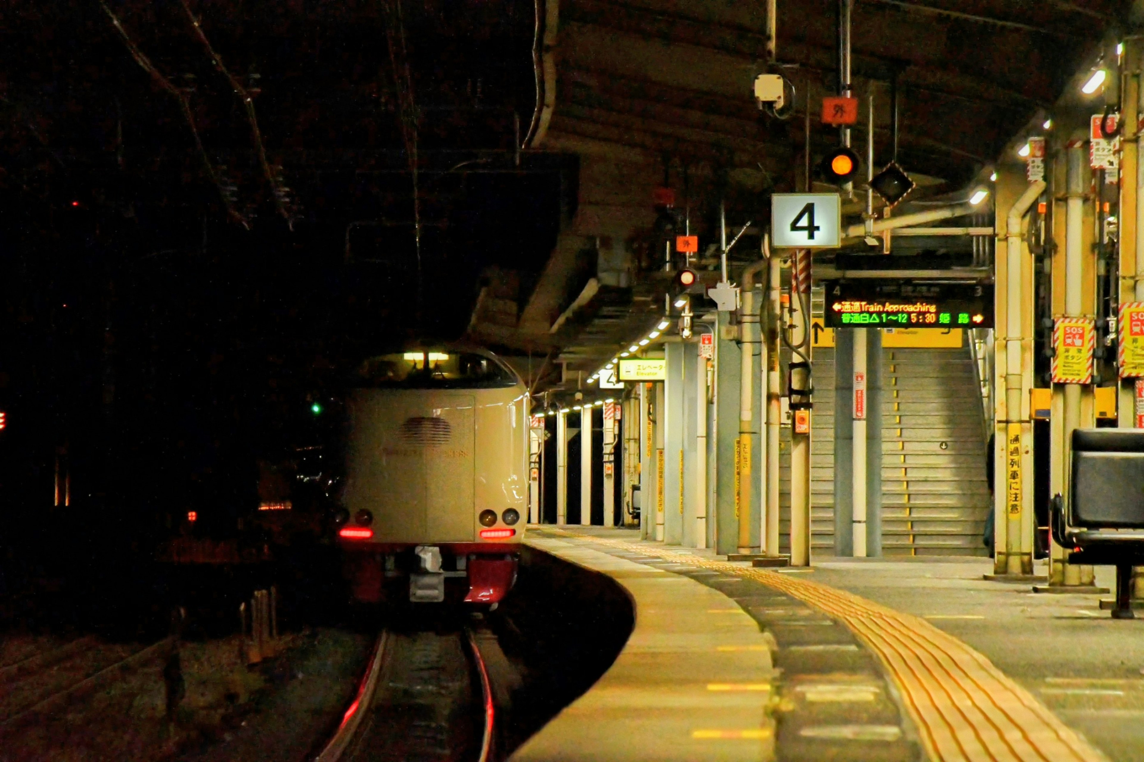 Train at a platform in a dimly lit station with stairs