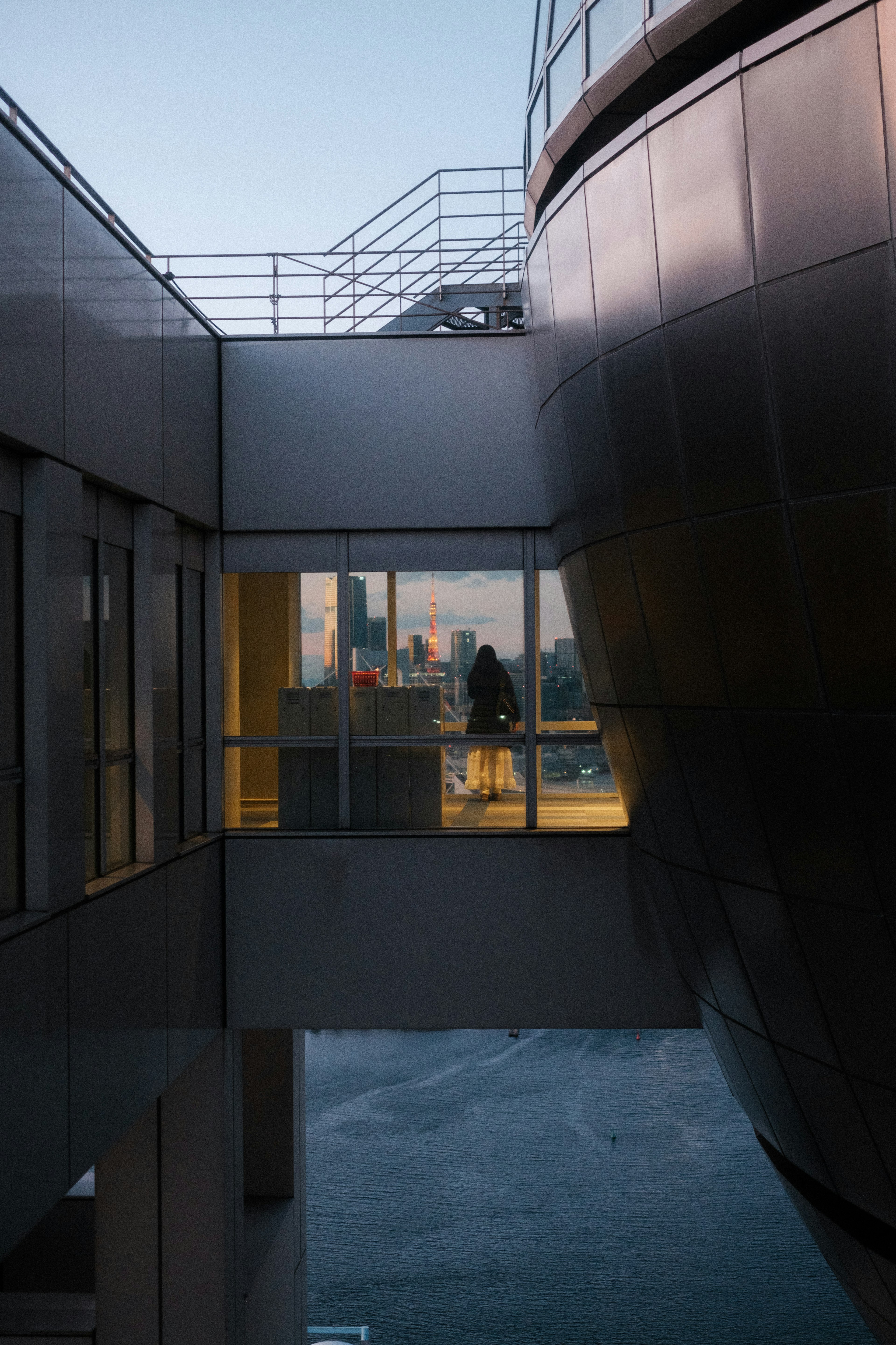 Personne se tenant derrière un mur en verre entre des bâtiments avec vue sur la ville