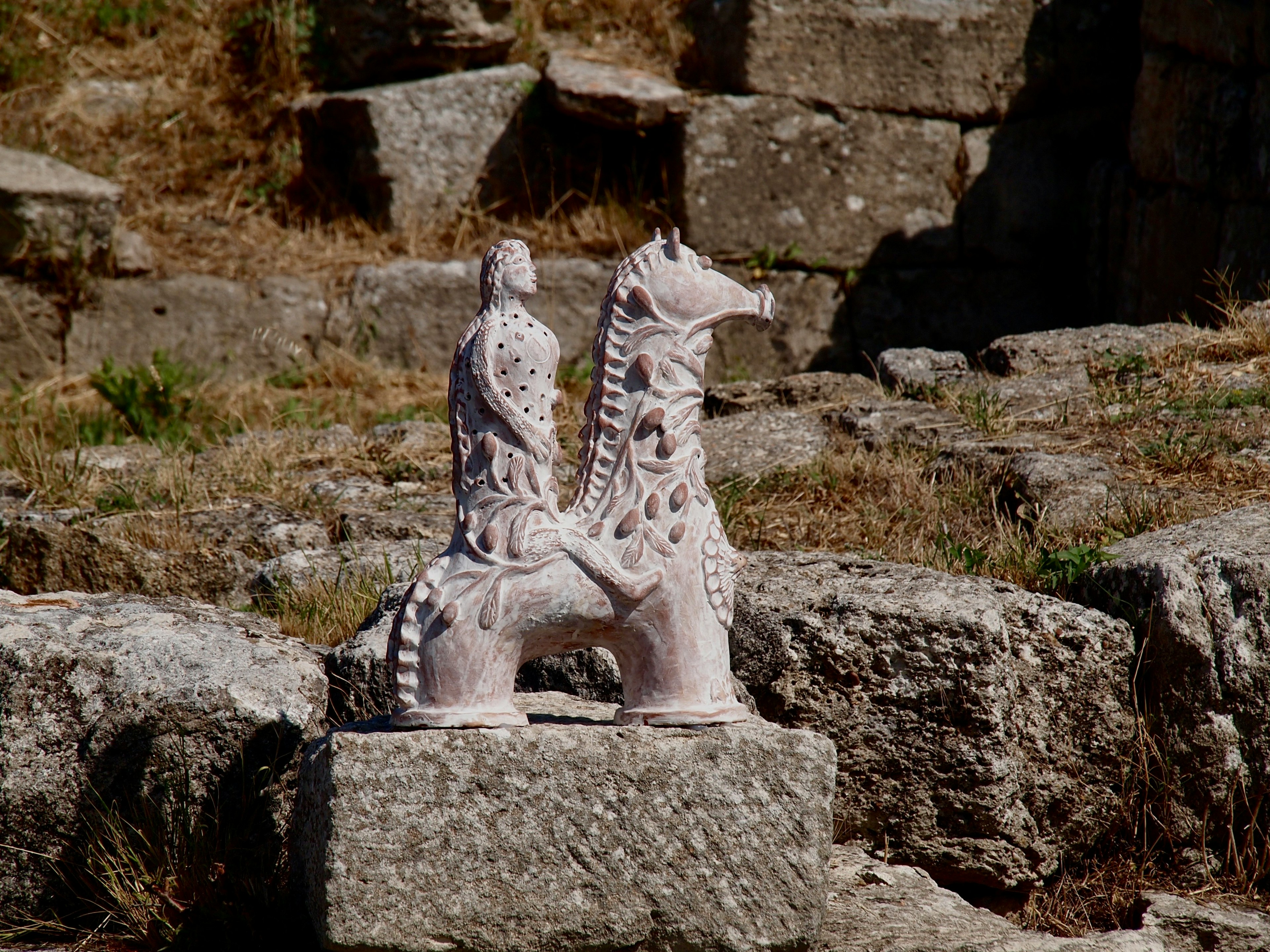 Scultura antica di una figura che cavalca un cavallo su una pietra