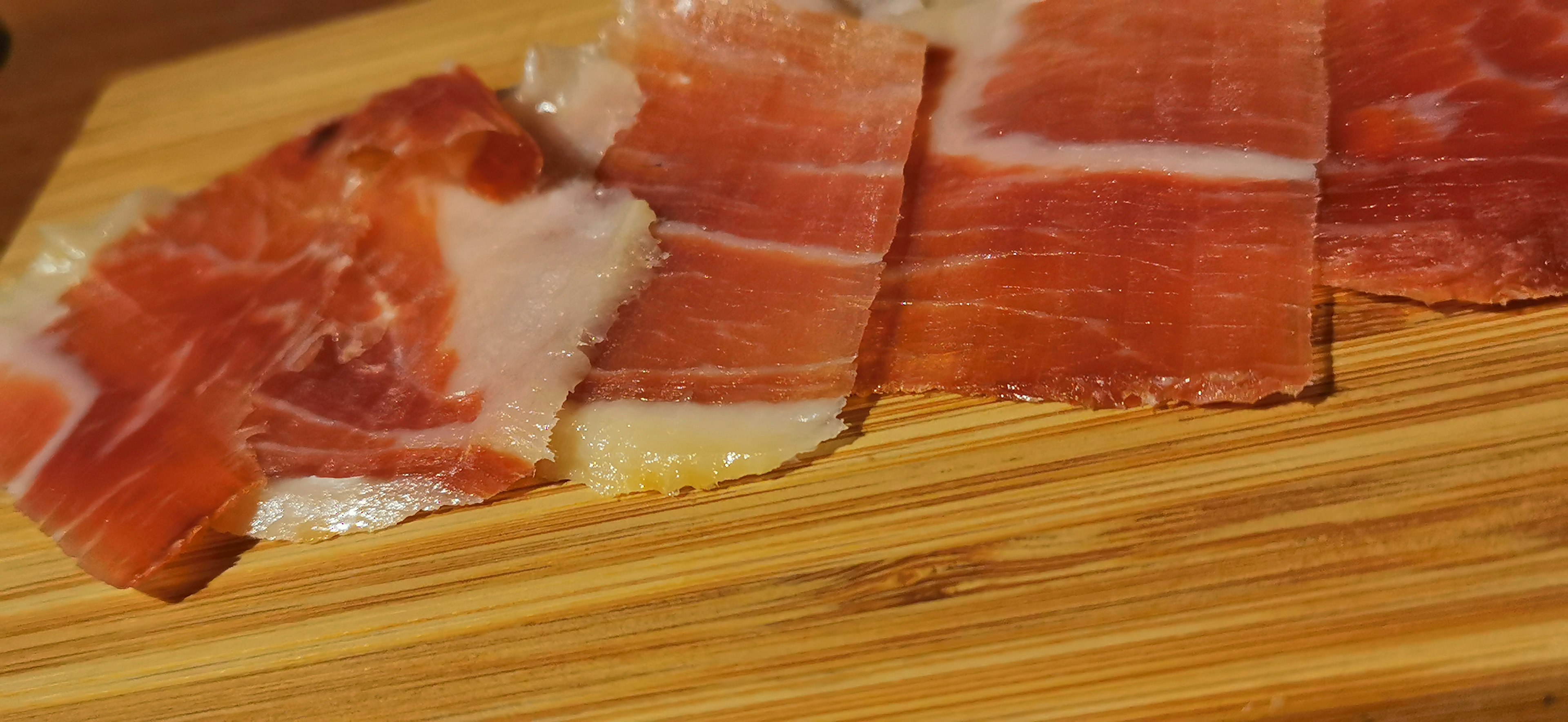 Fette di prosciutto disposte su un tagliere di legno