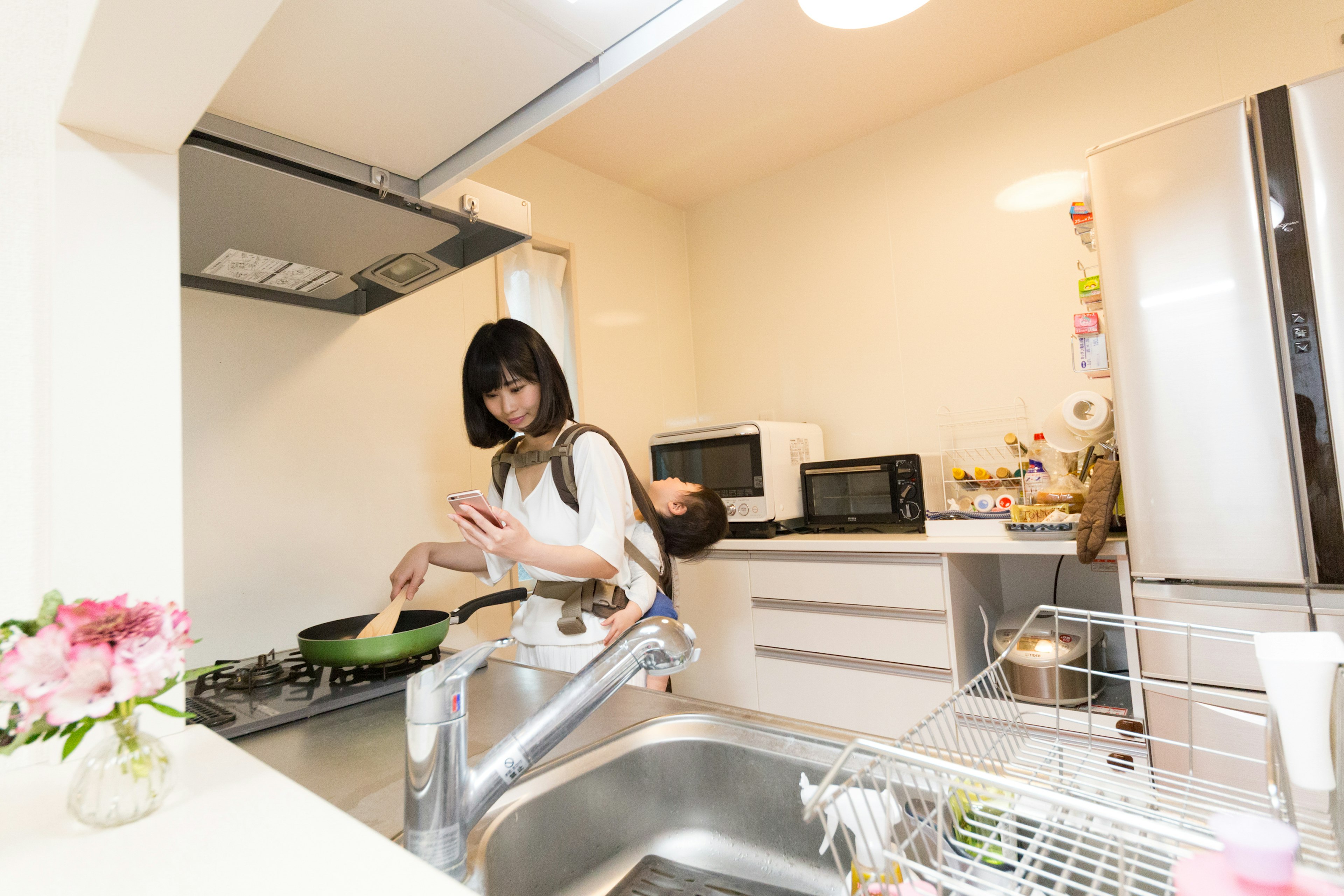 A woman cooking in a bright kitchen with a baby