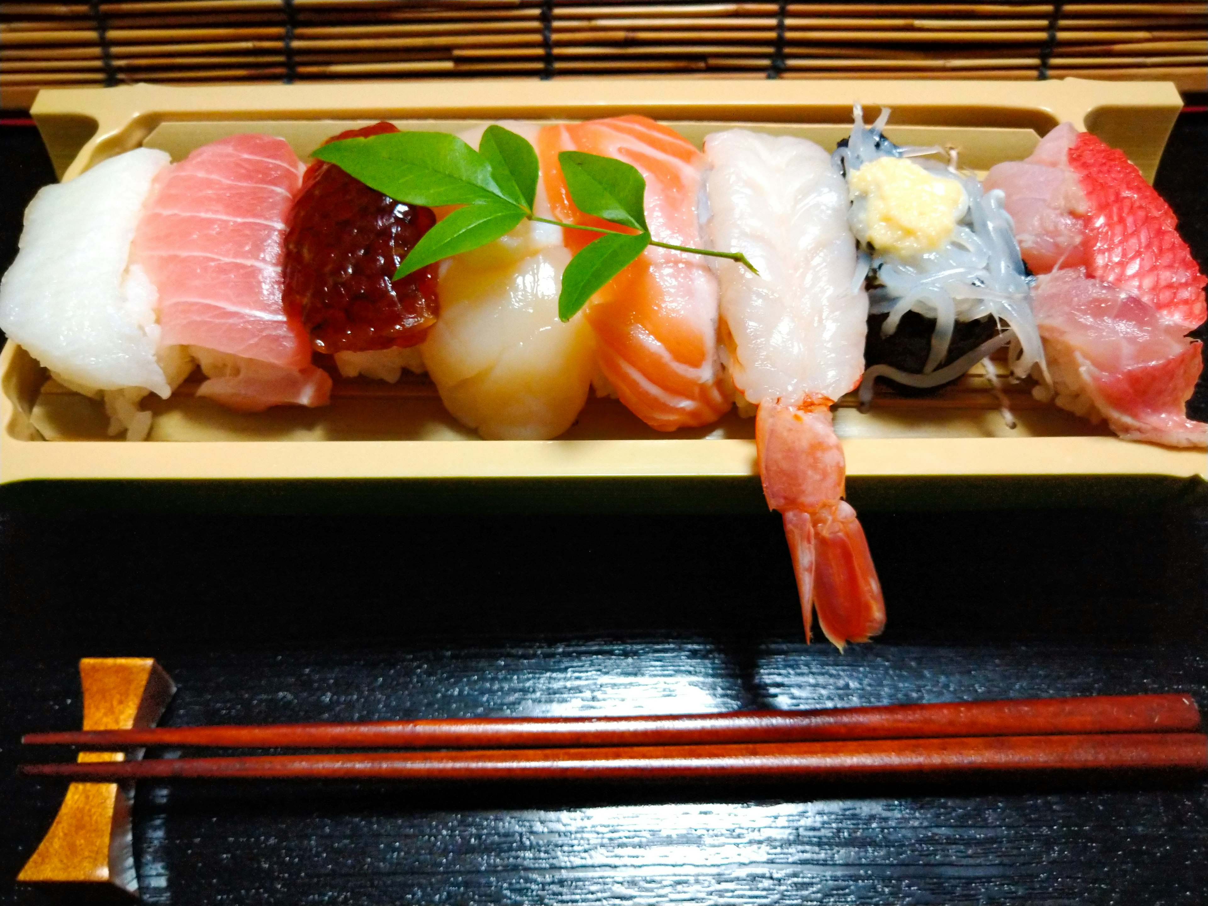 A beautiful assortment of sushi presented on a bamboo plate with chopsticks