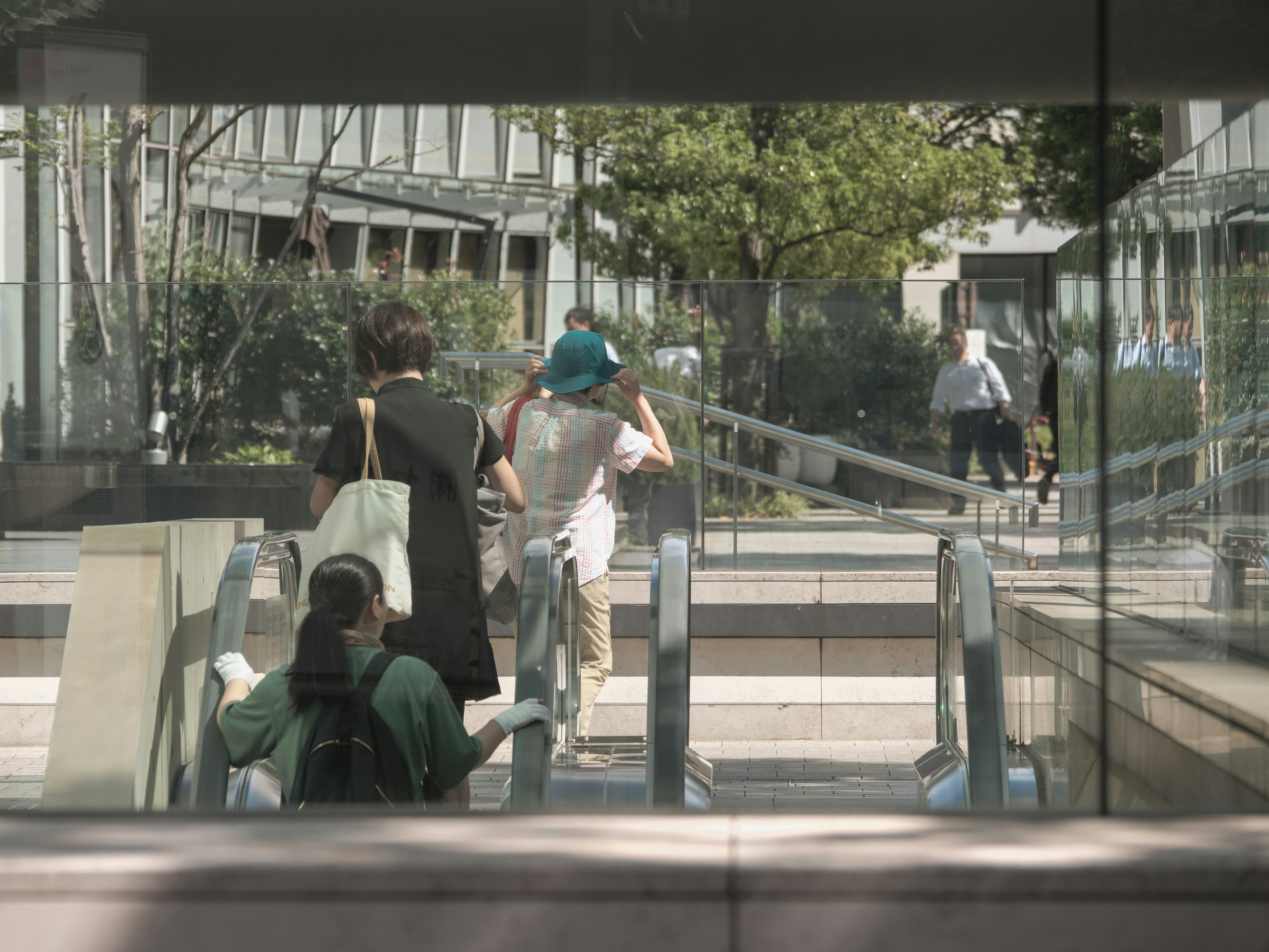 Personas moviéndose frente a escaleras mecánicas vistas a través del vidrio