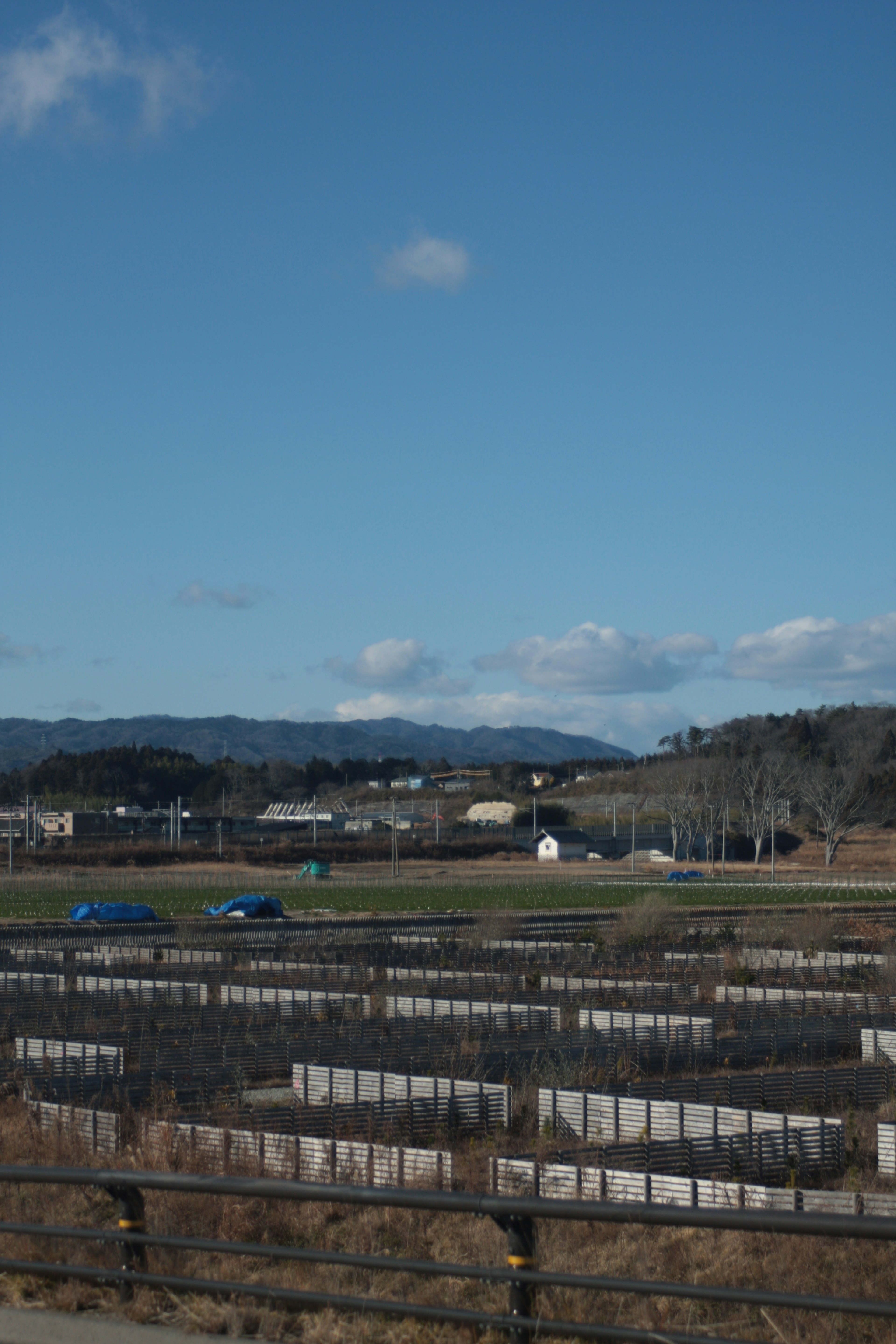 Landschaft mit Ackerland und Bergen unter einem blauen Himmel