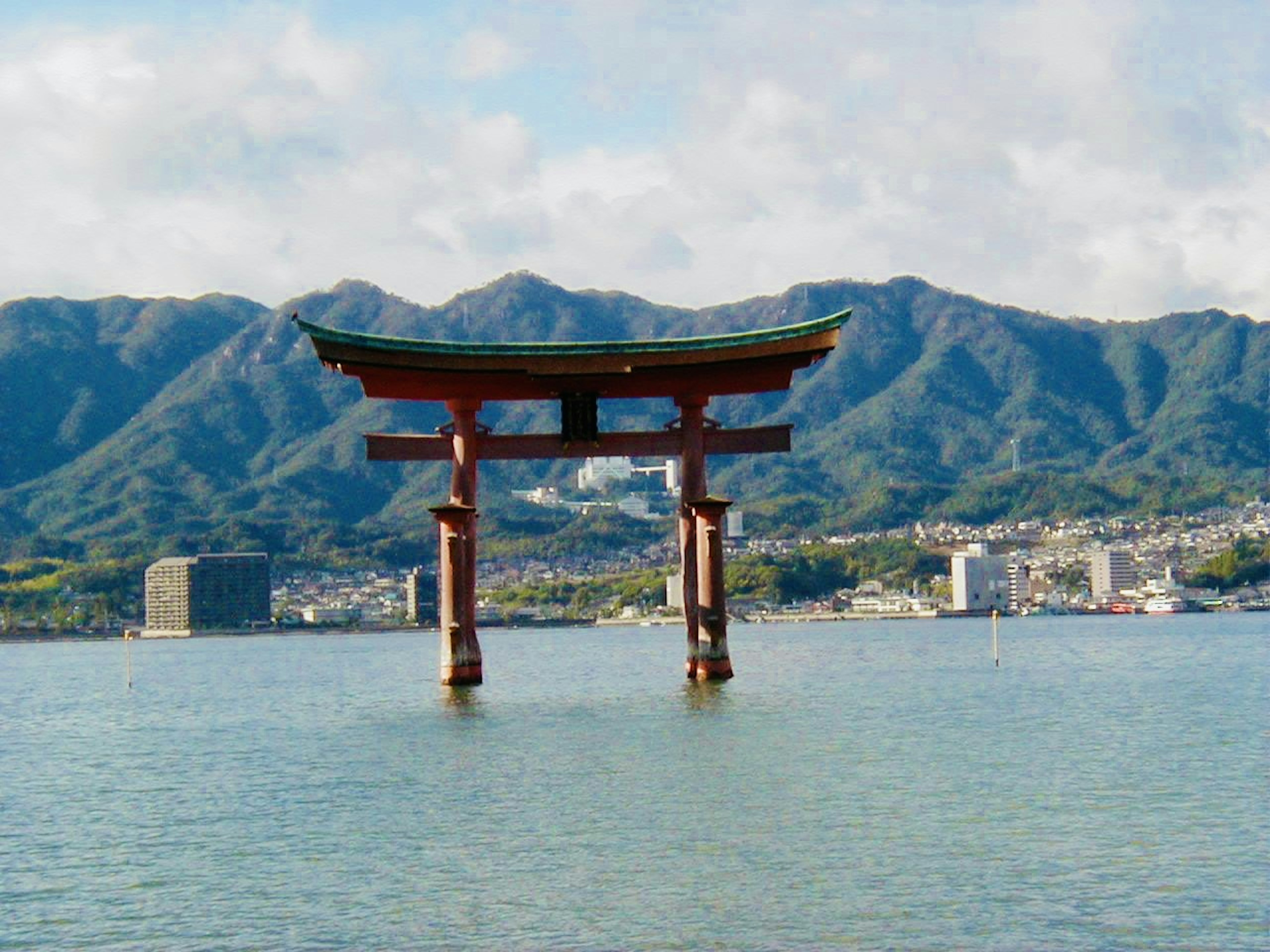 Torii rouge flottant dans la mer avec des montagnes en arrière-plan