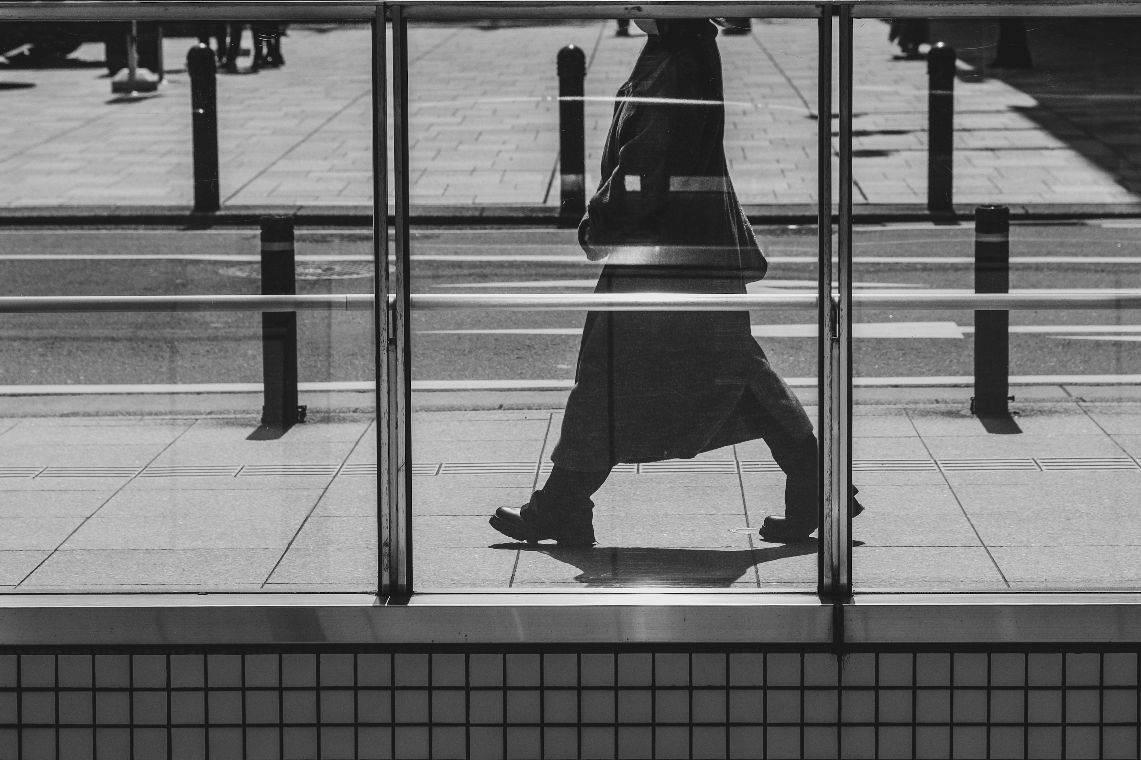 Silhouette of a person walking behind a glass barrier