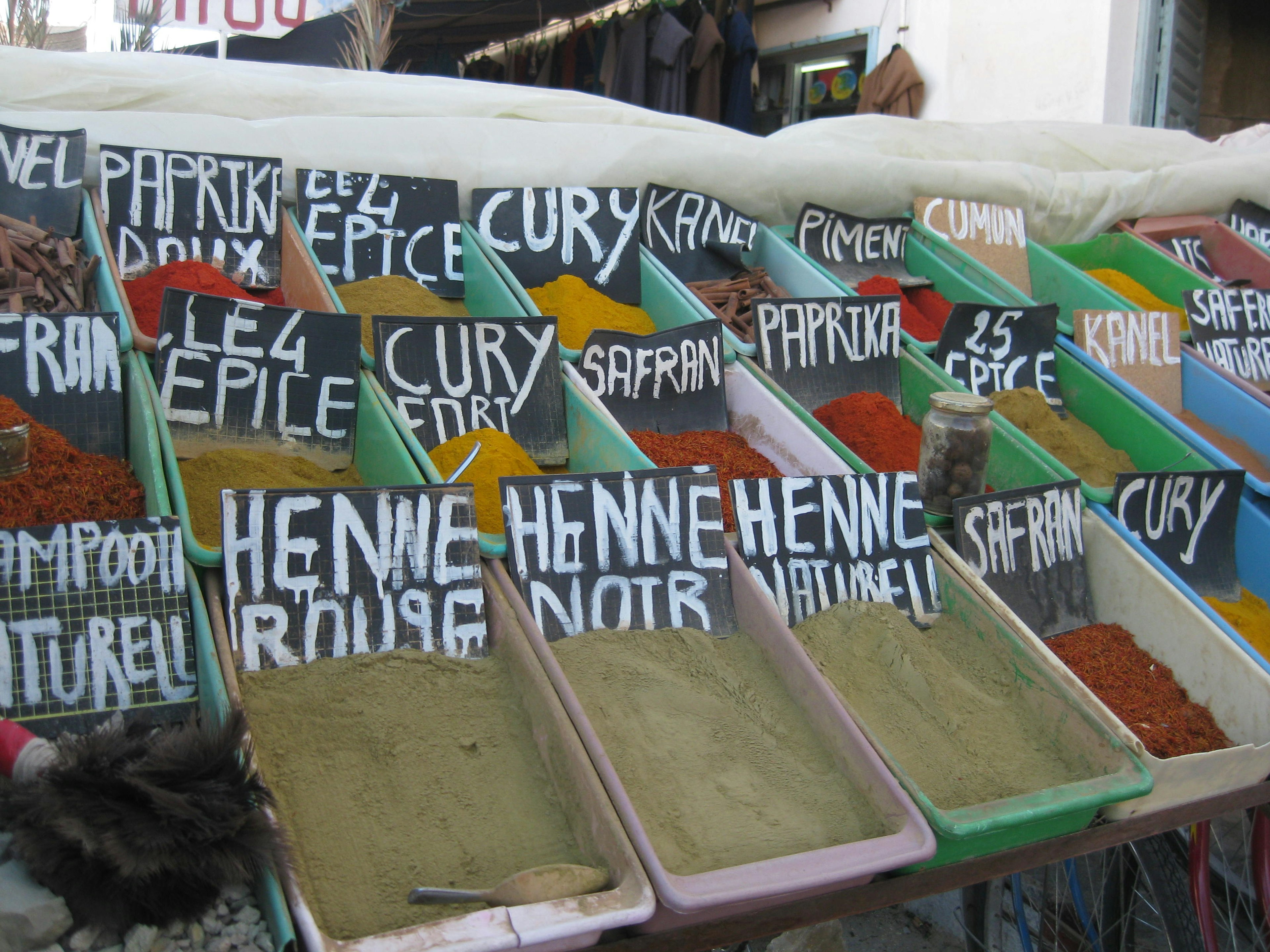 Colorful spice containers at a market with large white labels