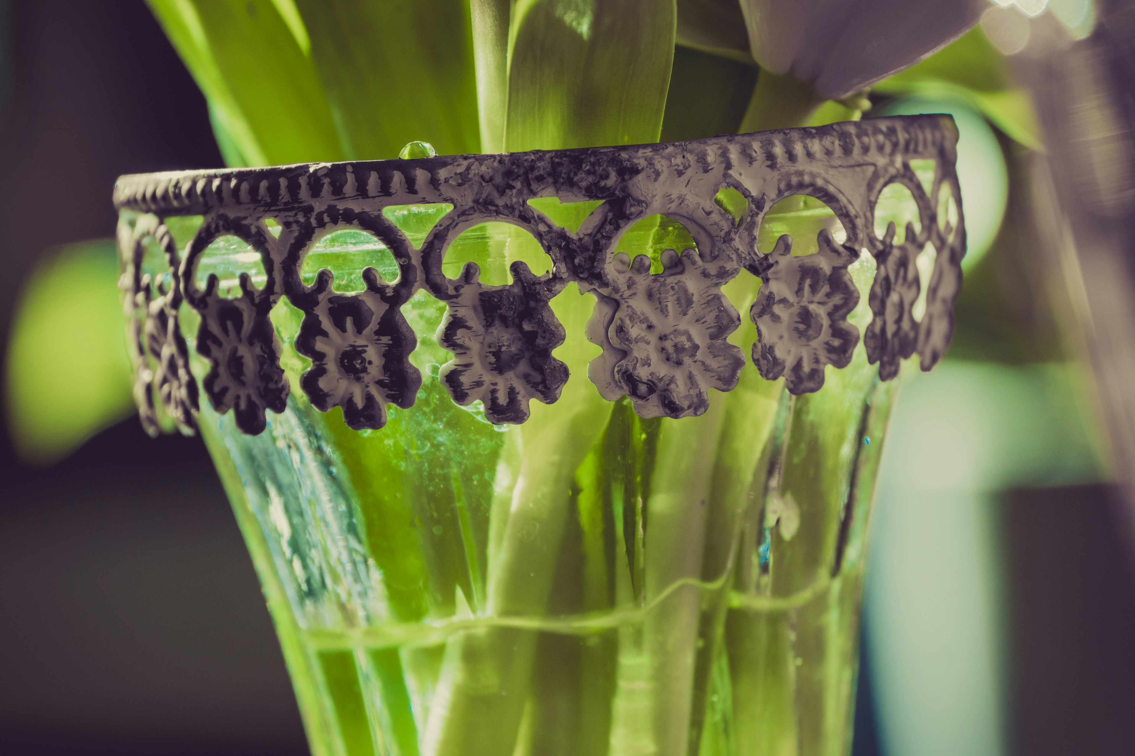 Close-up of a green vase with decorative metal rim