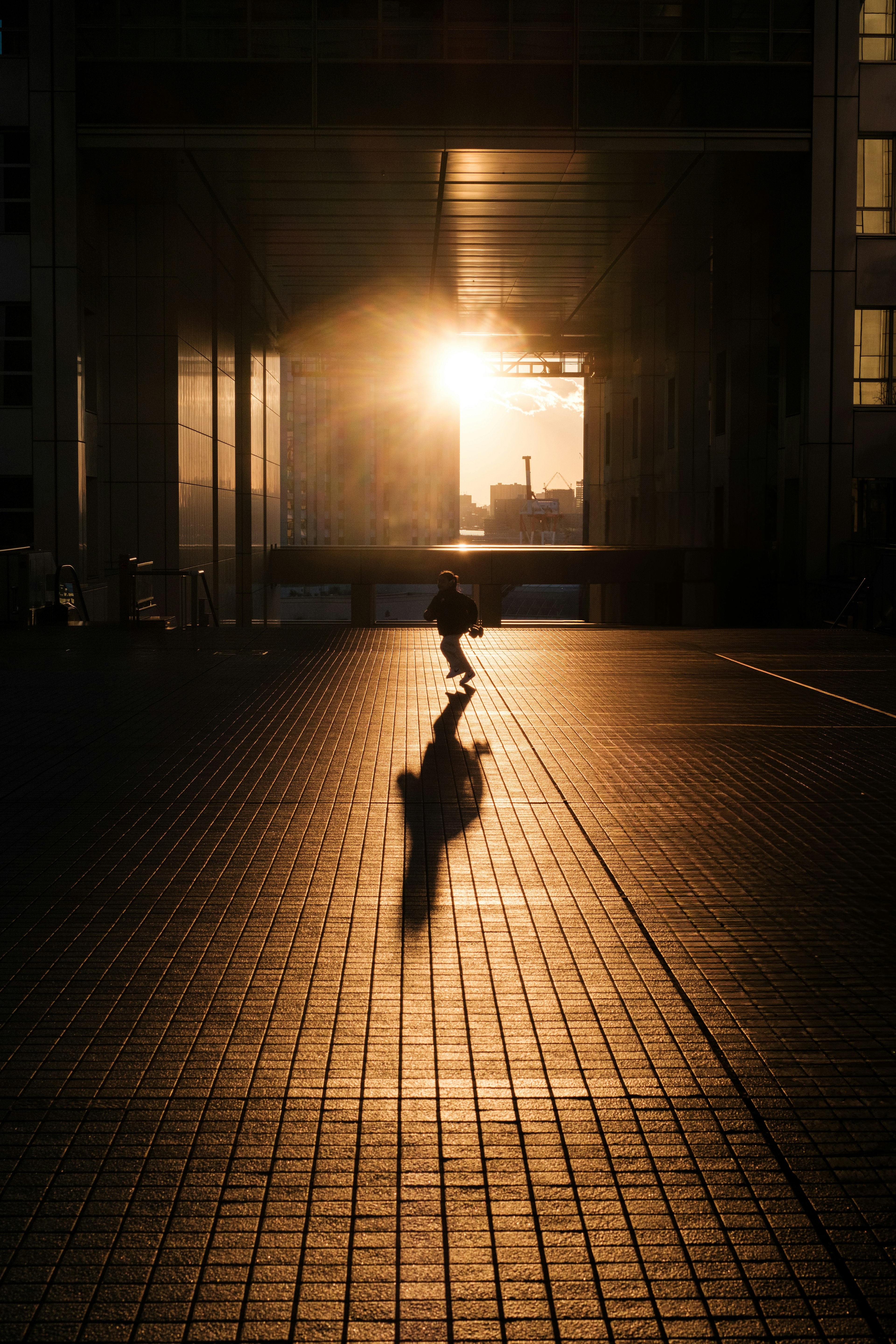 夕日を背にしたスケーターのシルエットが見える街の風景