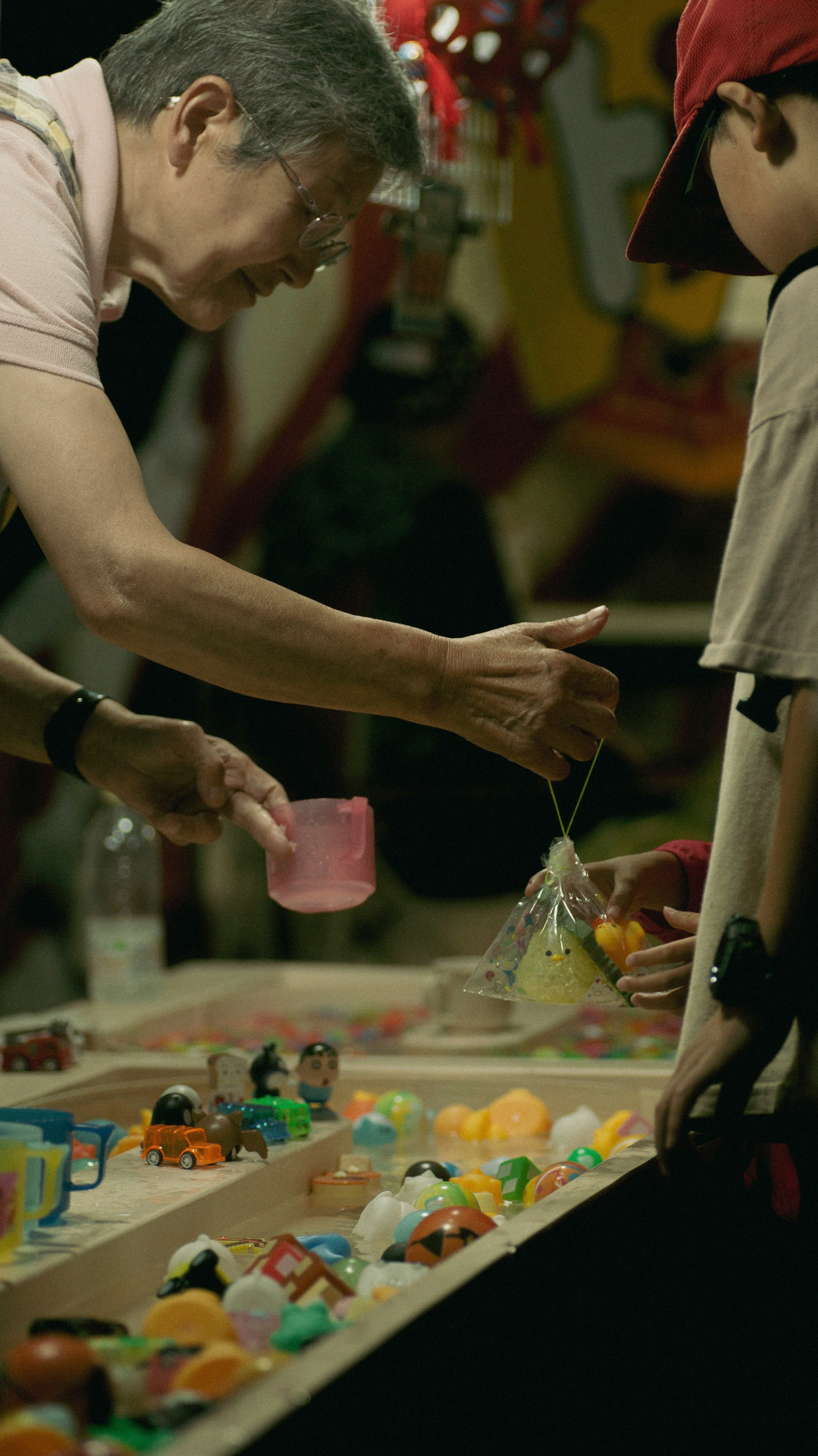 An elderly man and a child selecting colorful toys at a festival