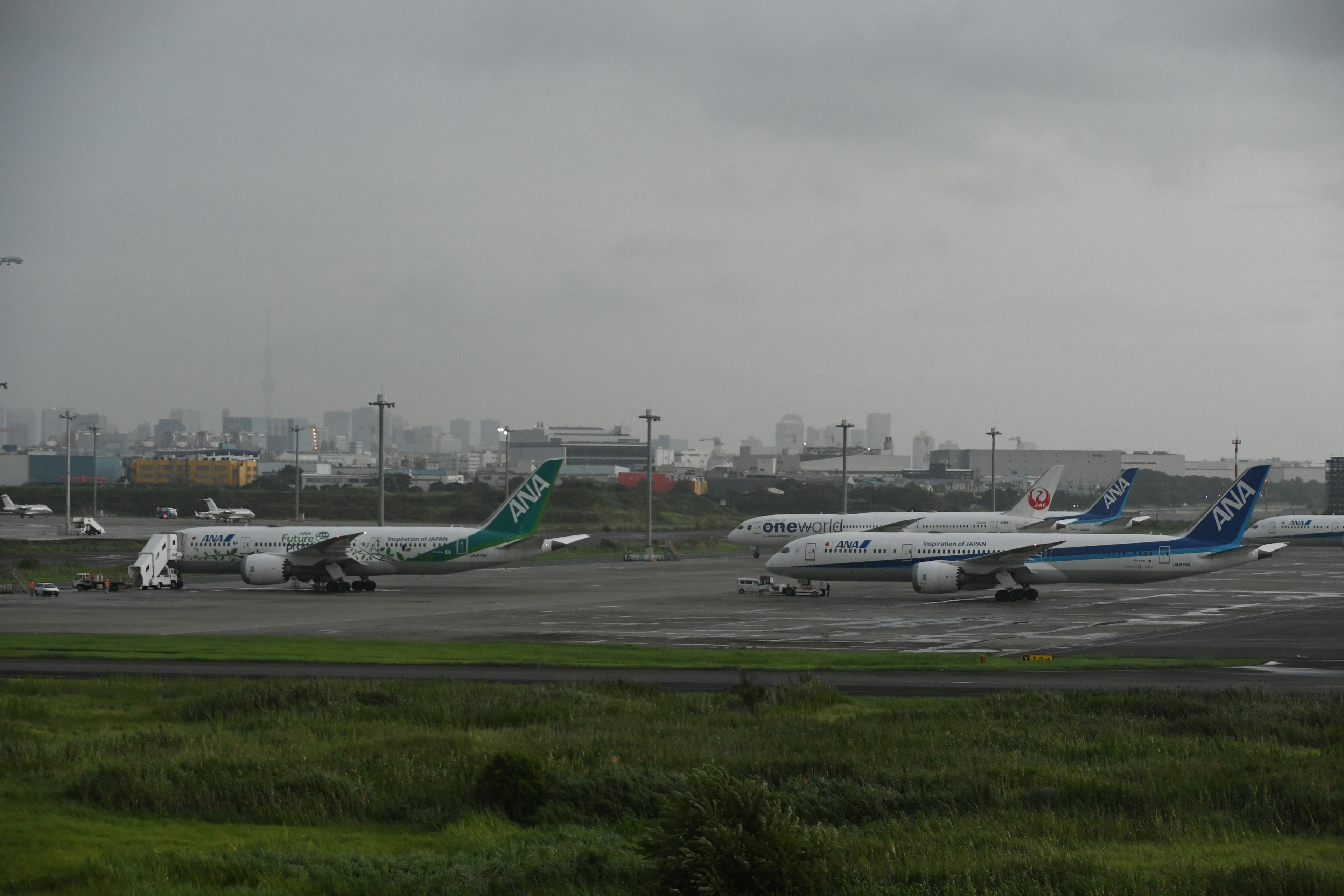 Multiple aircraft parked on an airport runway under overcast sky