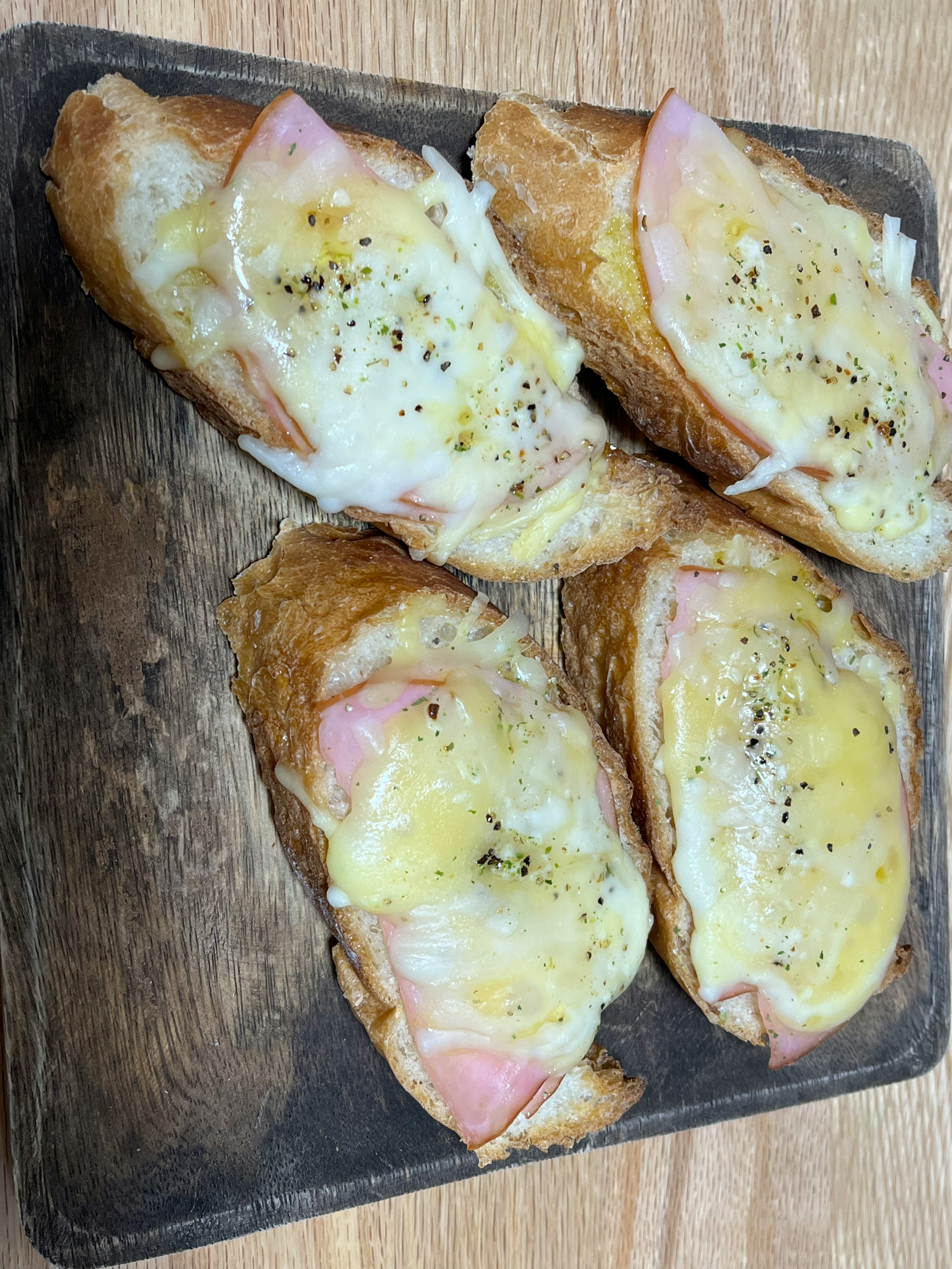 Toasted cheese and ham sandwiches arranged on a wooden platter