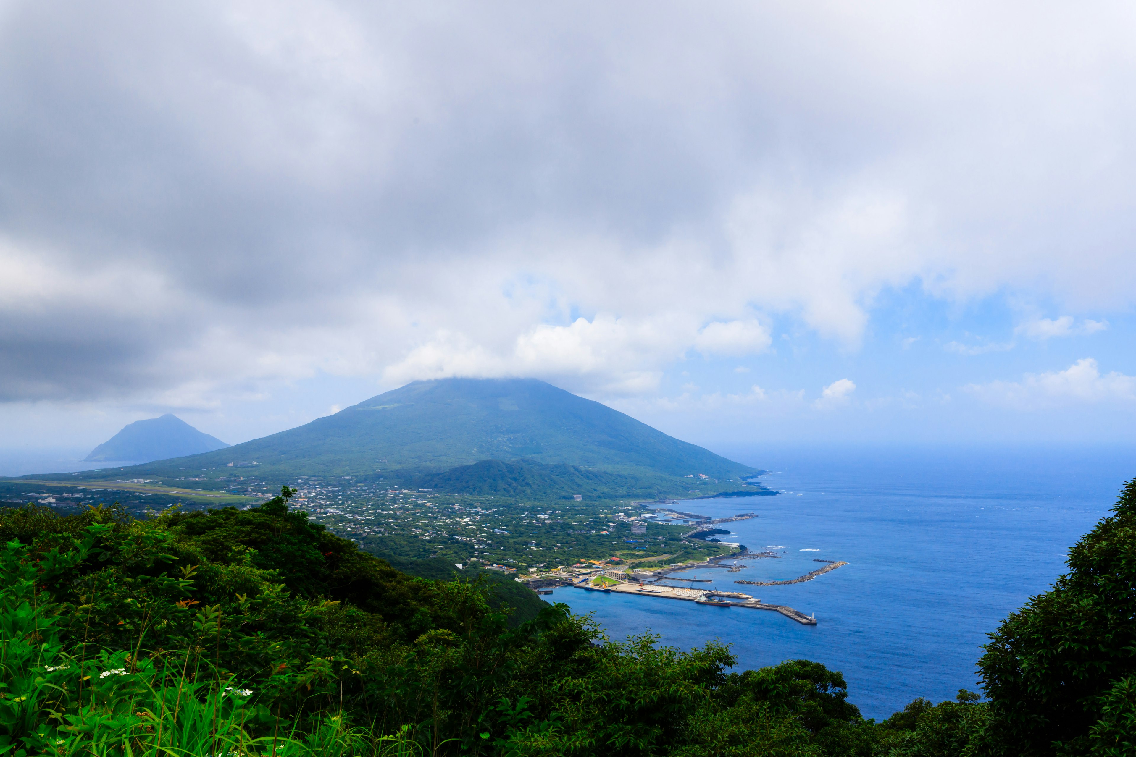 Vista panoramica di montagne e oceano blu sotto un cielo nuvoloso