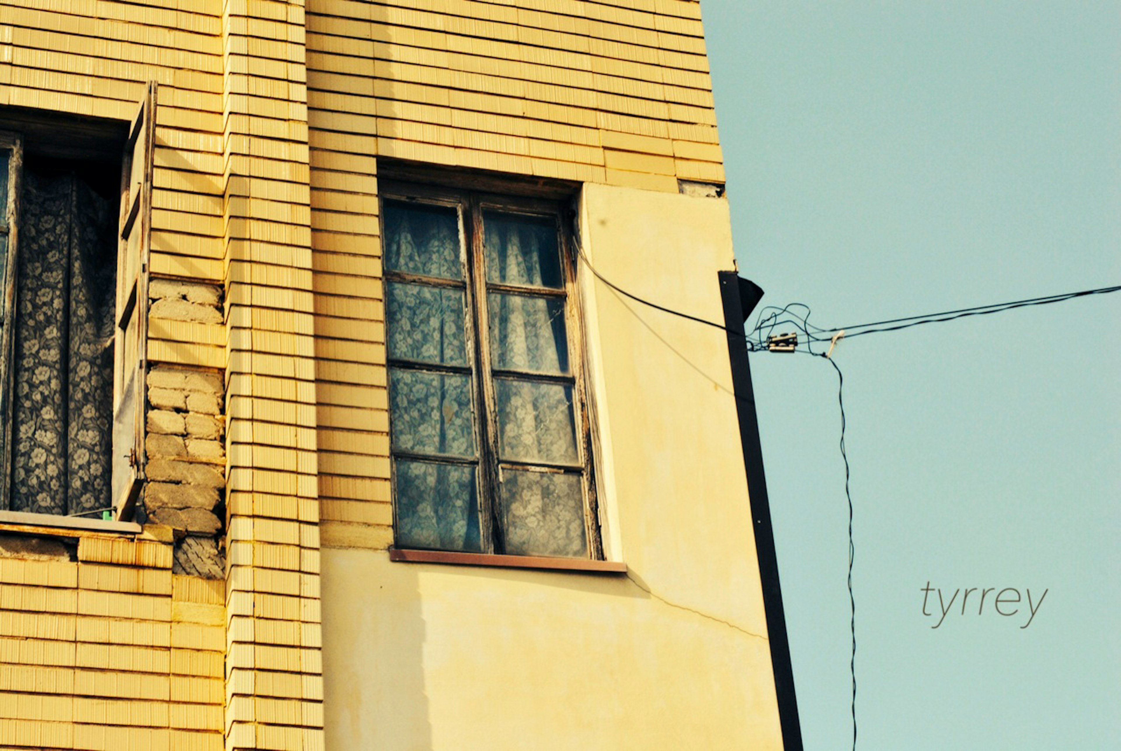 A building with yellow exterior featuring a window and power lines