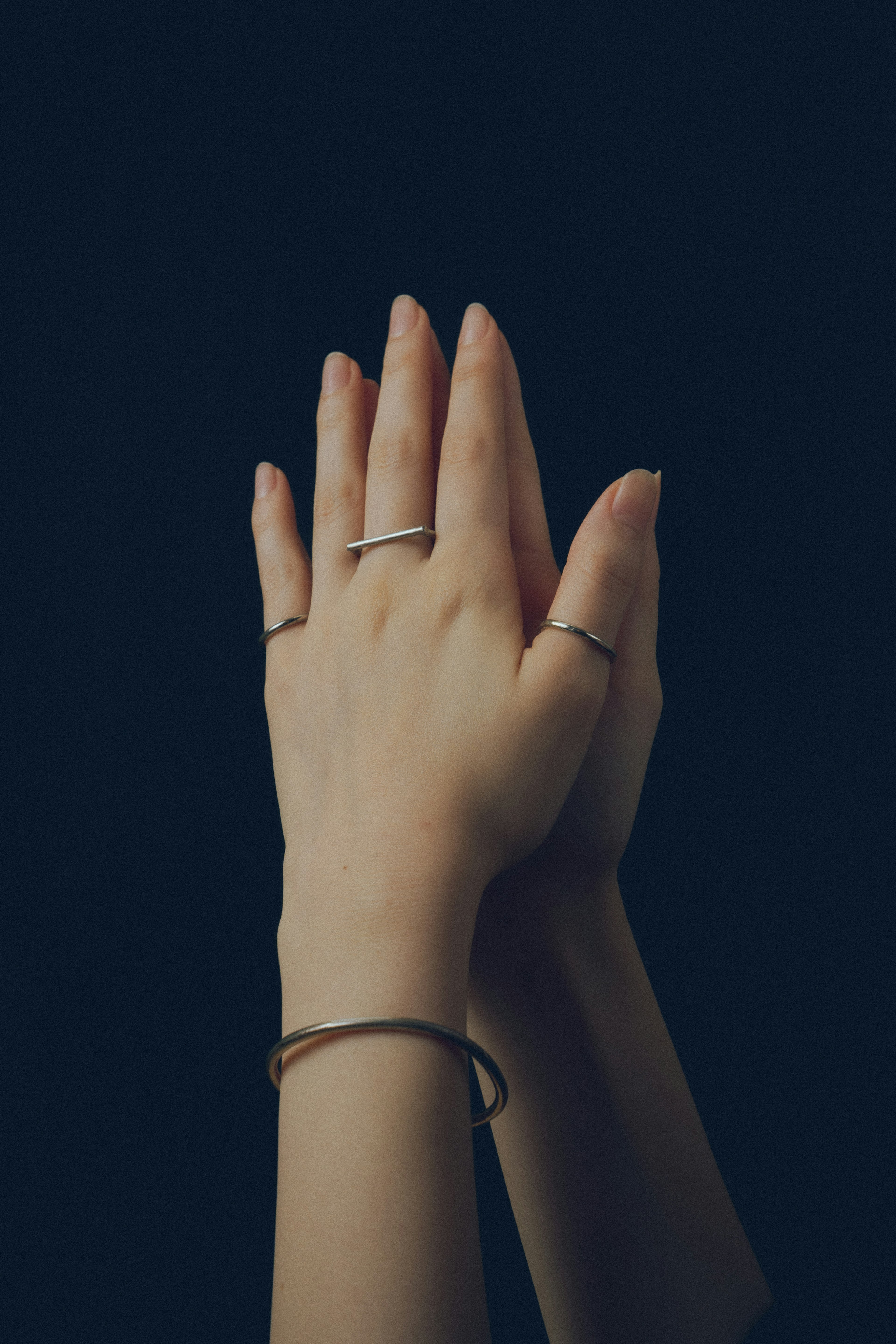 Image of hands clasped together featuring rings and bracelets