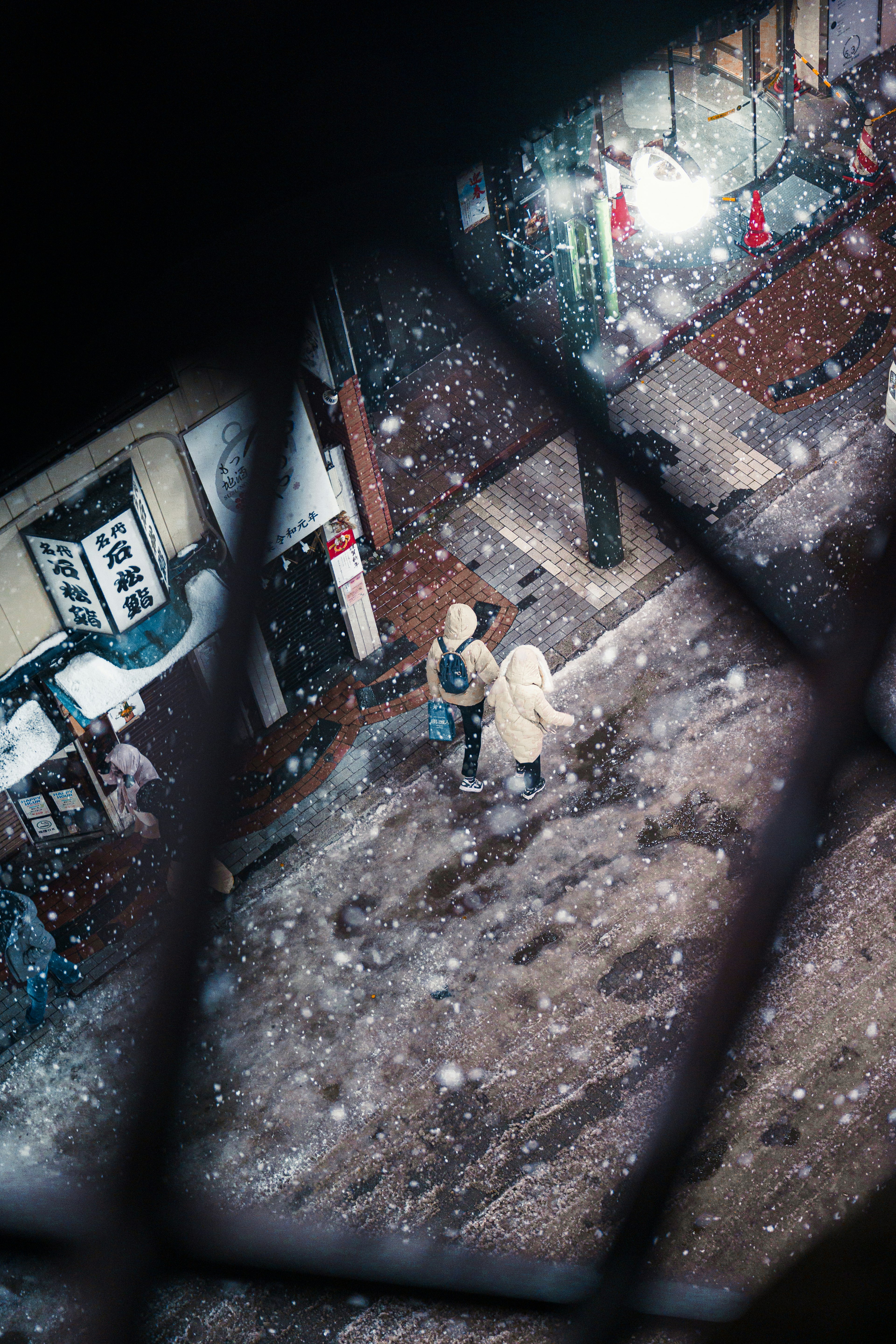 Two figures walking on a snowy street in a city