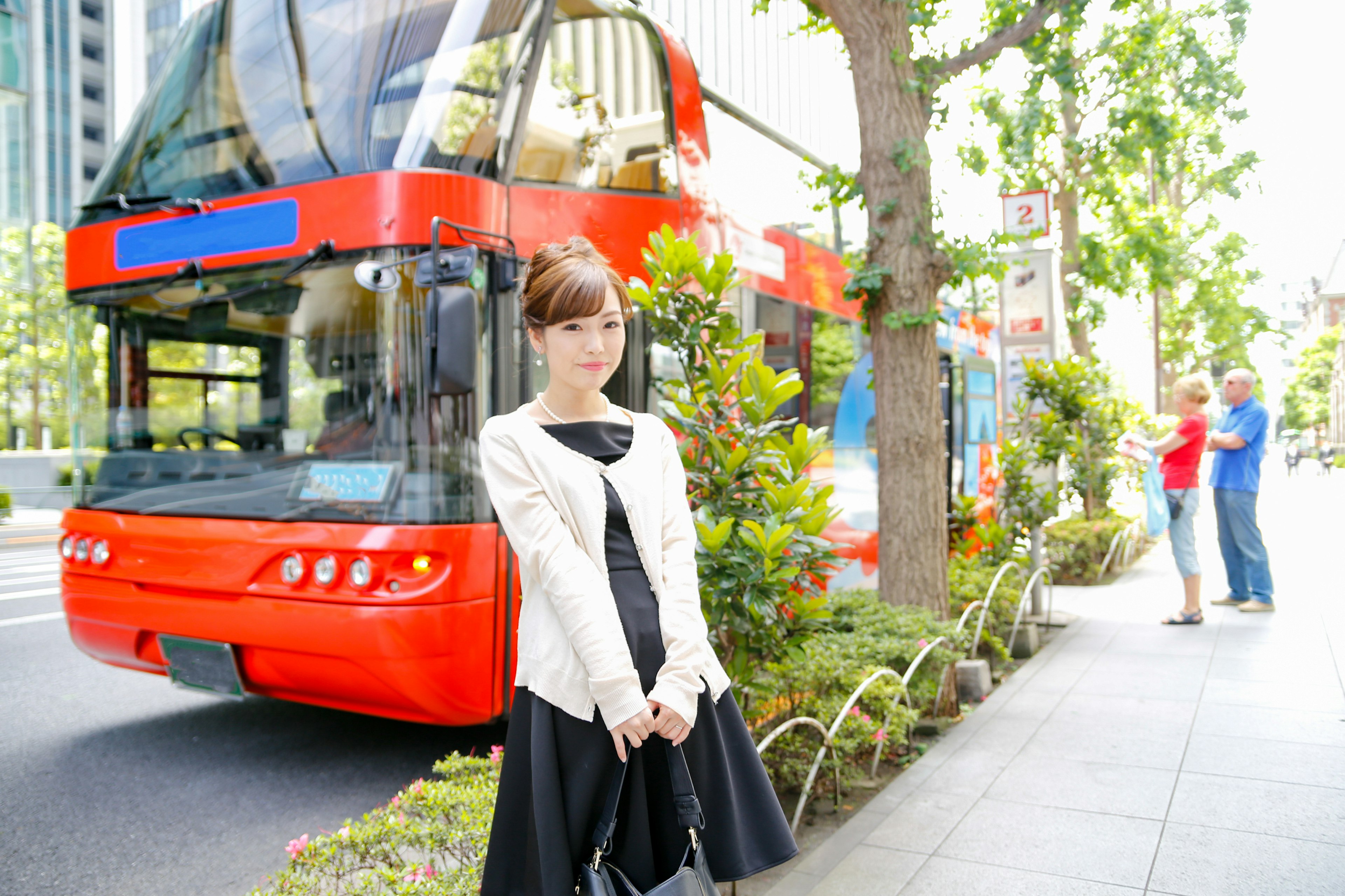 A woman standing in front of a red bus