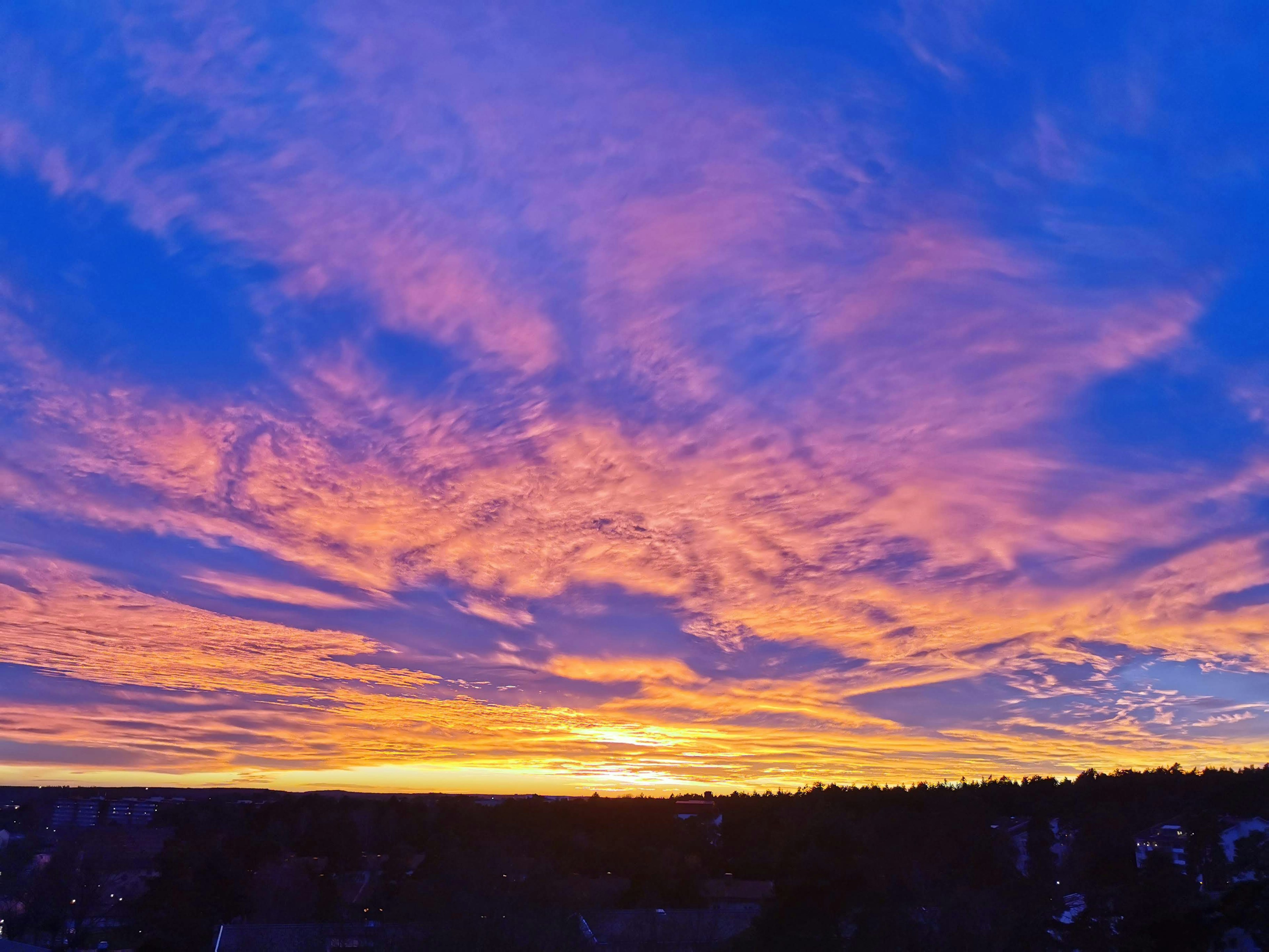 Cielo di tramonto vibrante con nuvole colorate e un orizzonte lontano