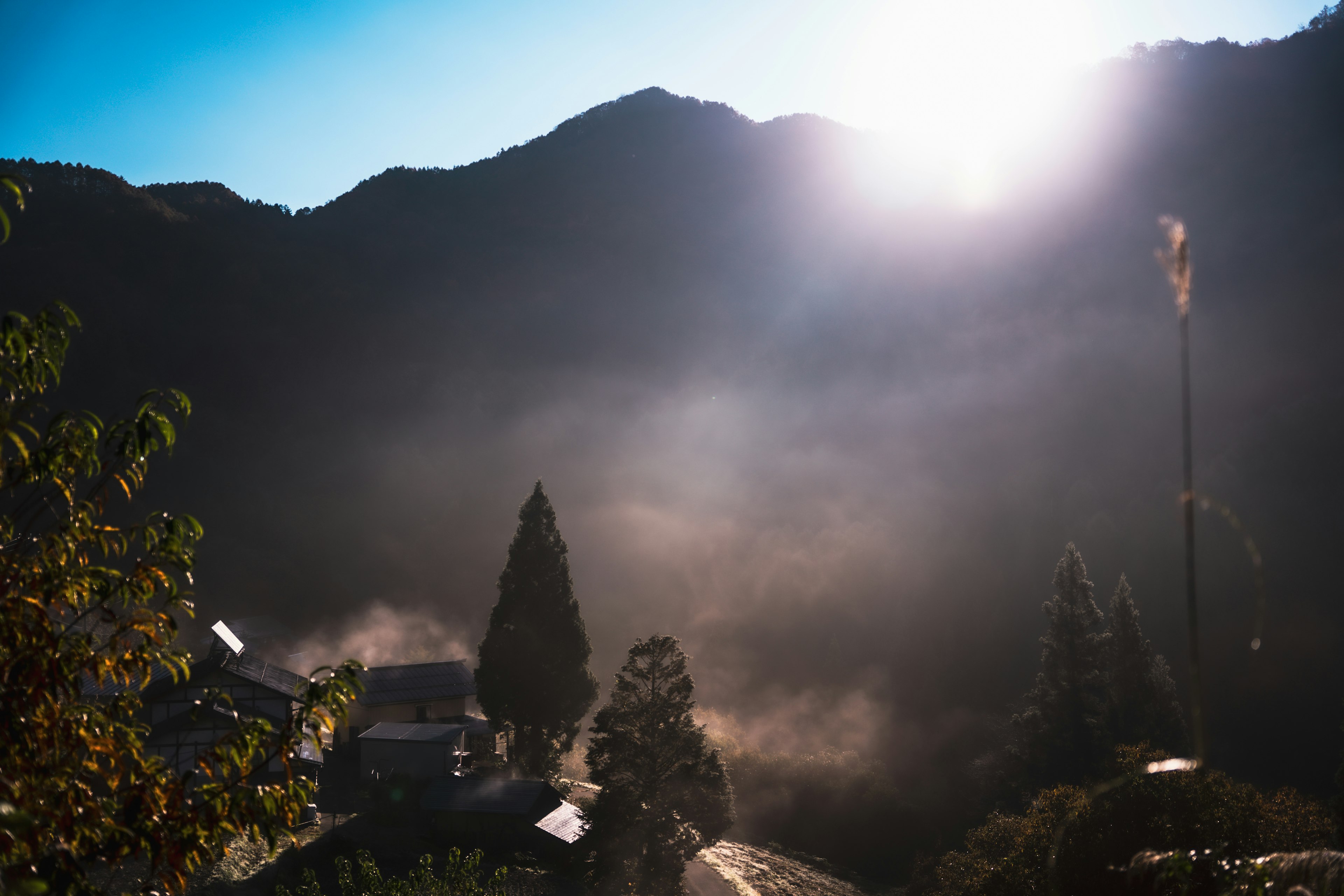 Mountain landscape at sunrise with mist enveloping trees and houses