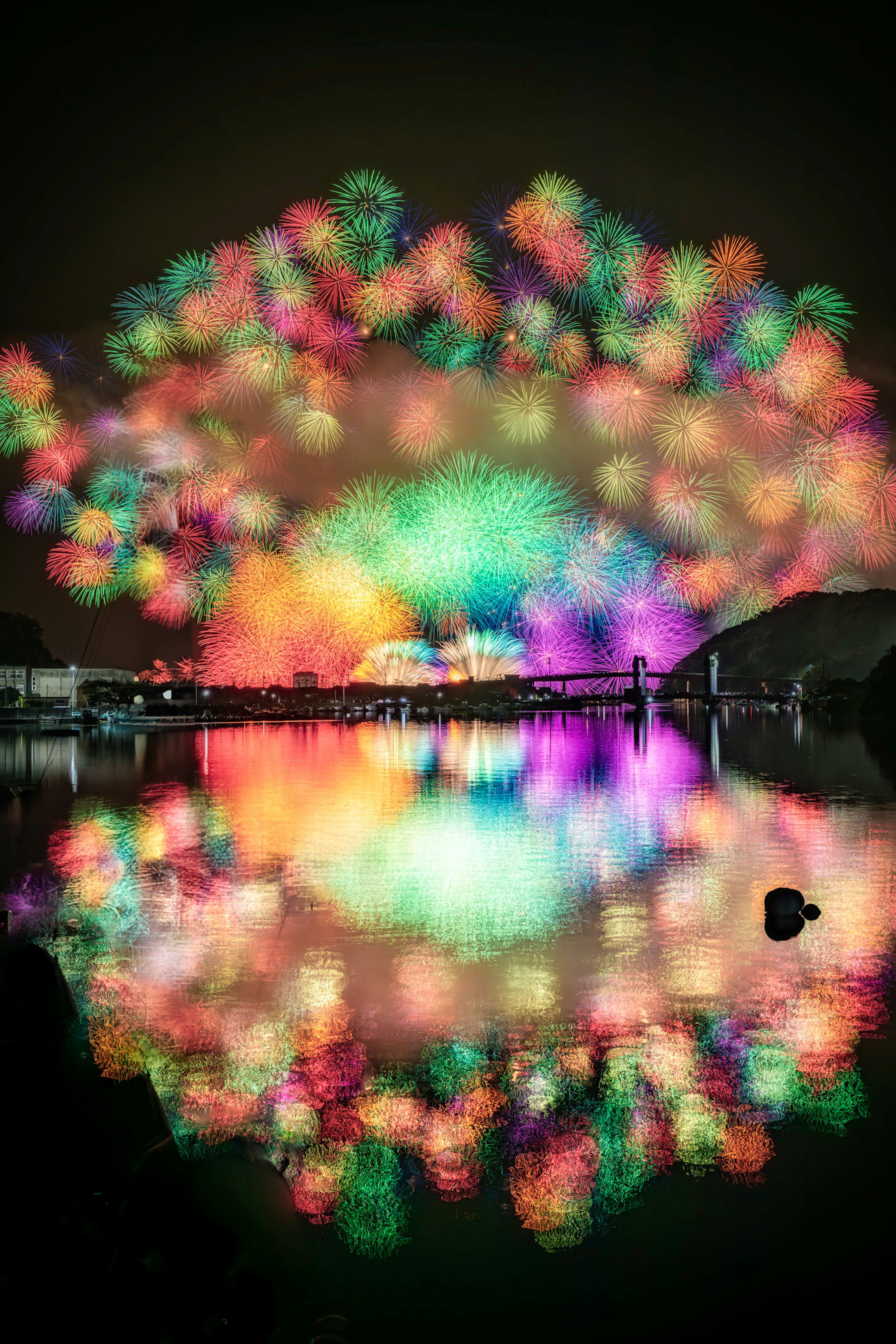 夜空に広がるカラフルな花火が湖に映る美しい光景