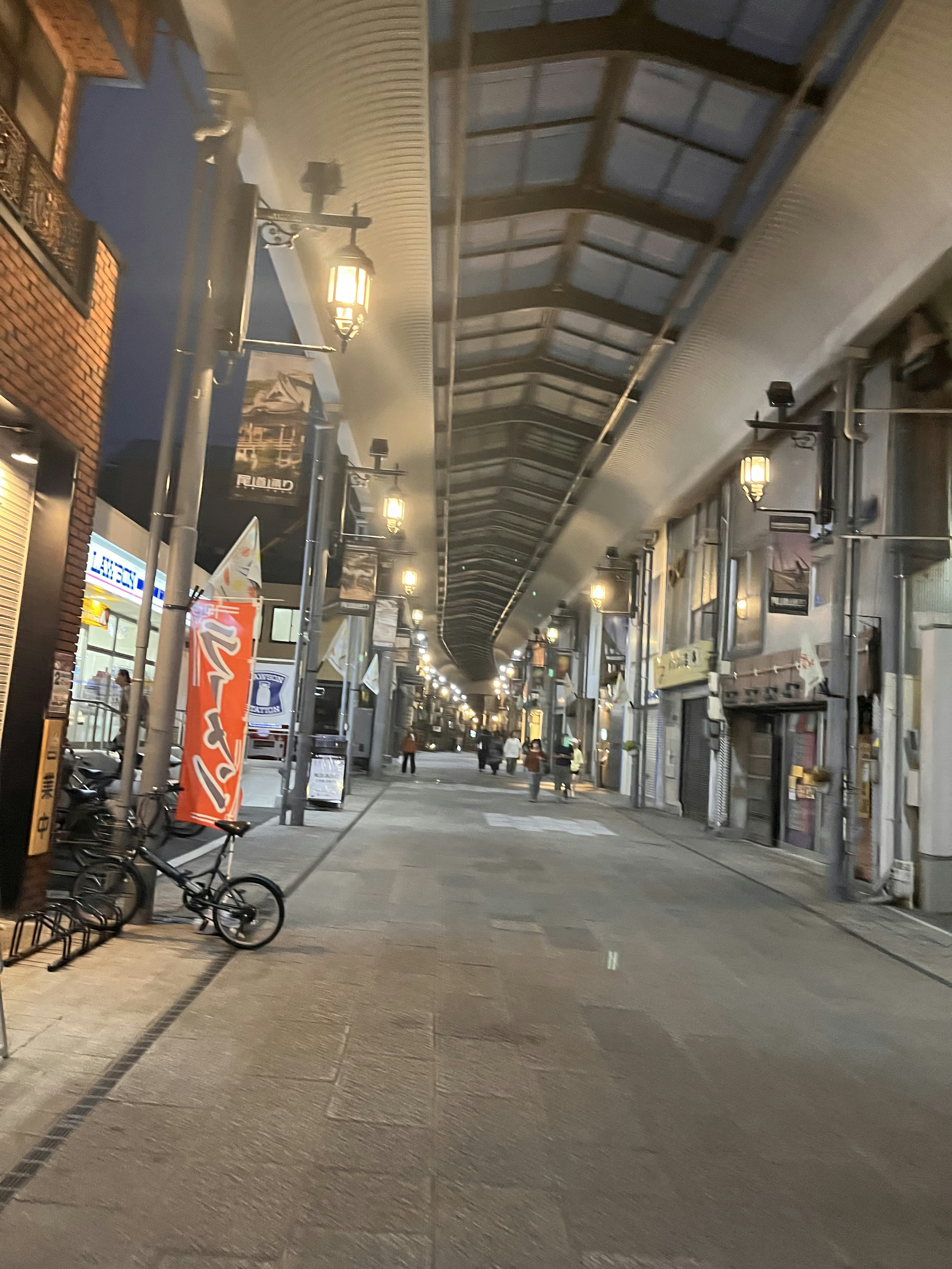 夜の商店街の静かな通り 照明が灯る屋根付きの歩道 自転車が停まる