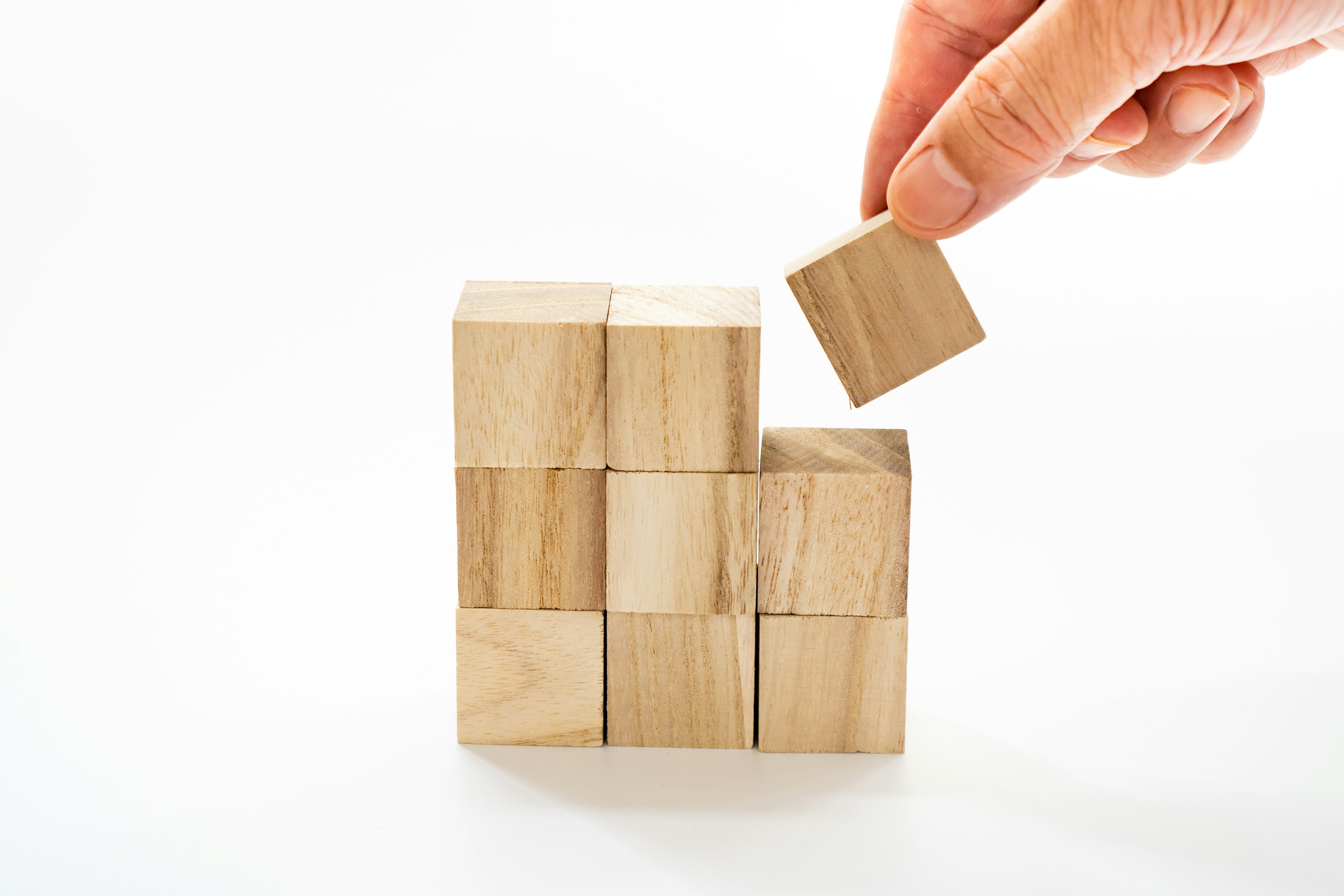 Image of a hand placing a wooden block on a stack