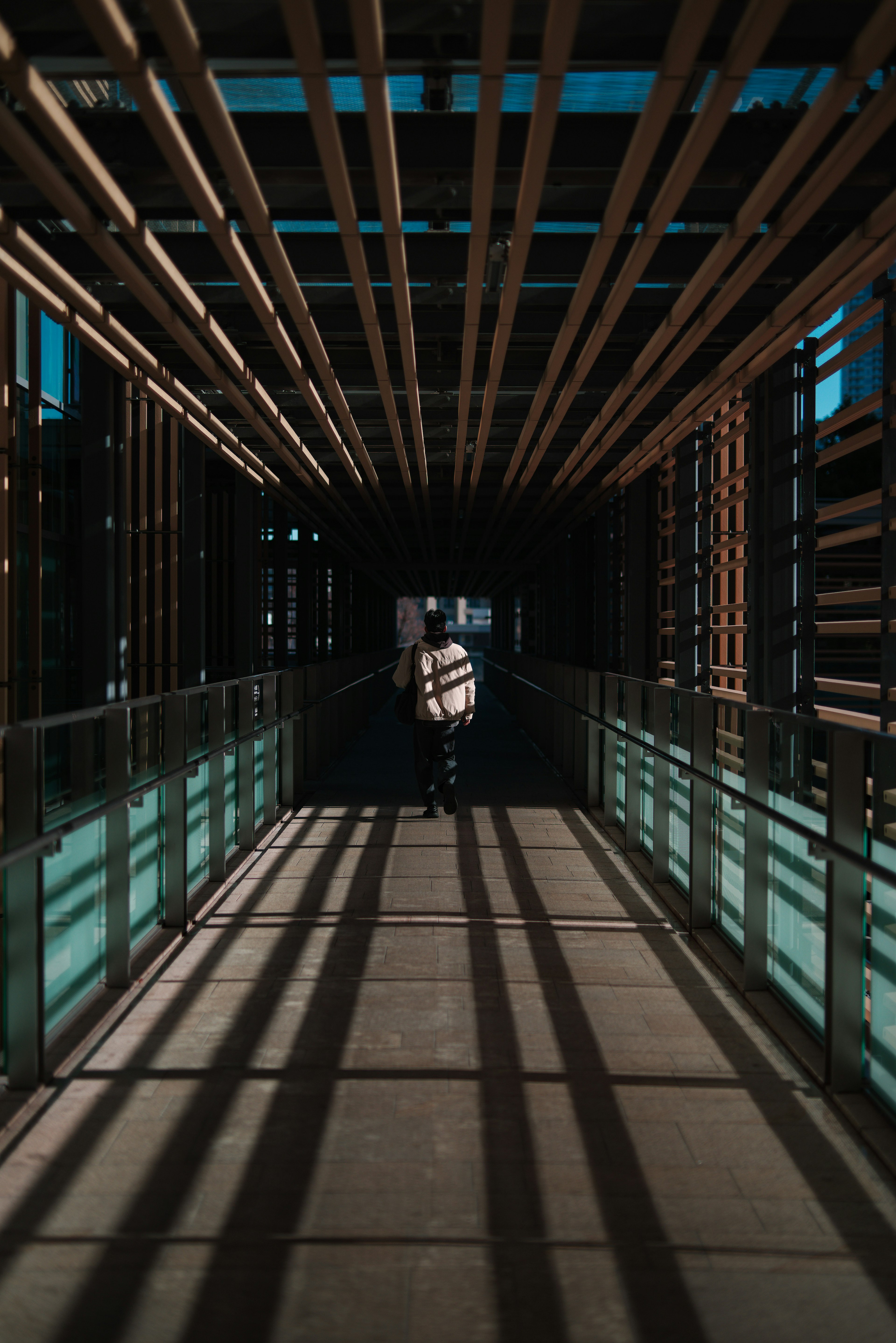 A person walking through a wooden-beamed corridor with shadows