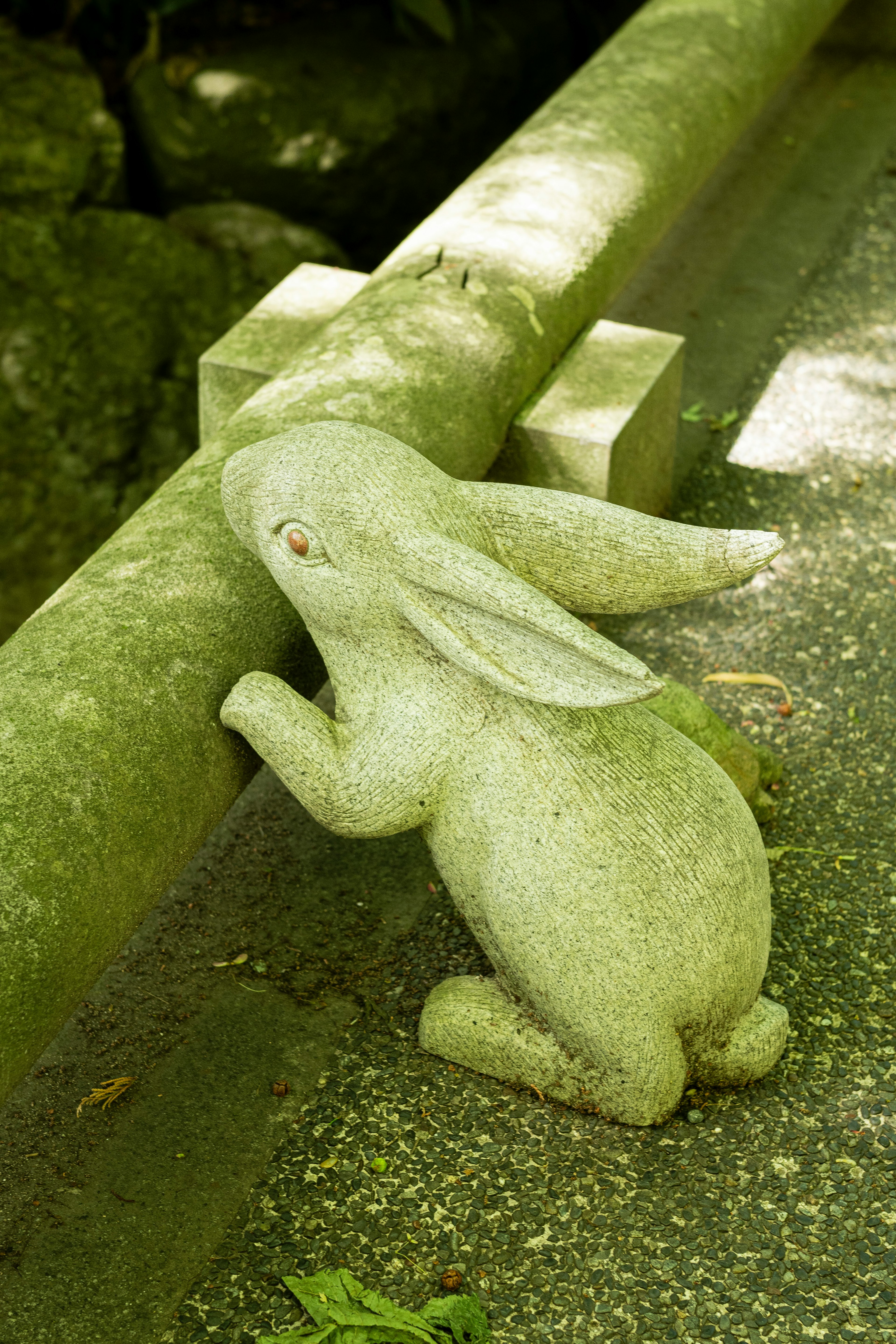 Escultura de conejo de piedra apoyada en una pared baja