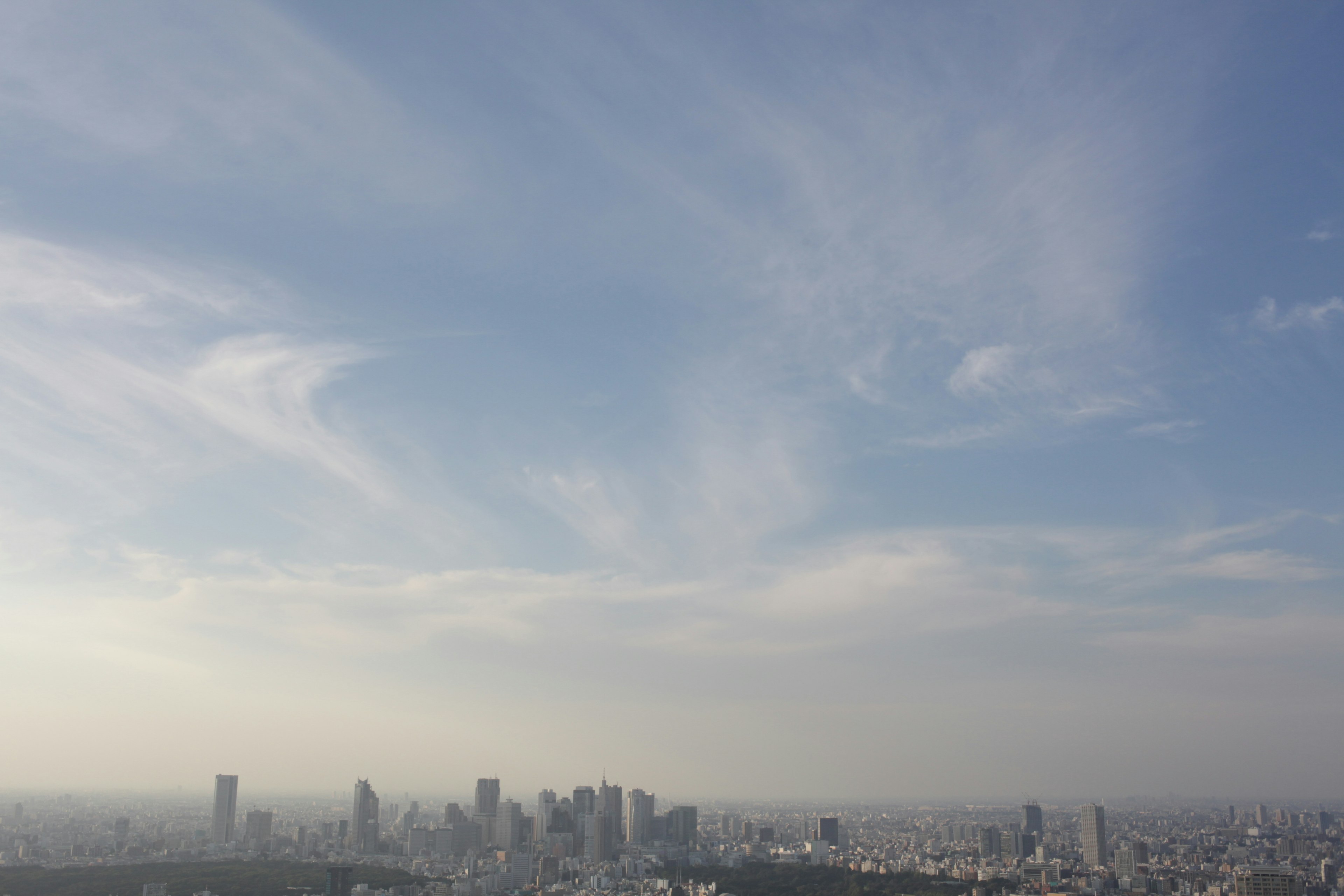 City skyline under a clear blue sky with wispy clouds