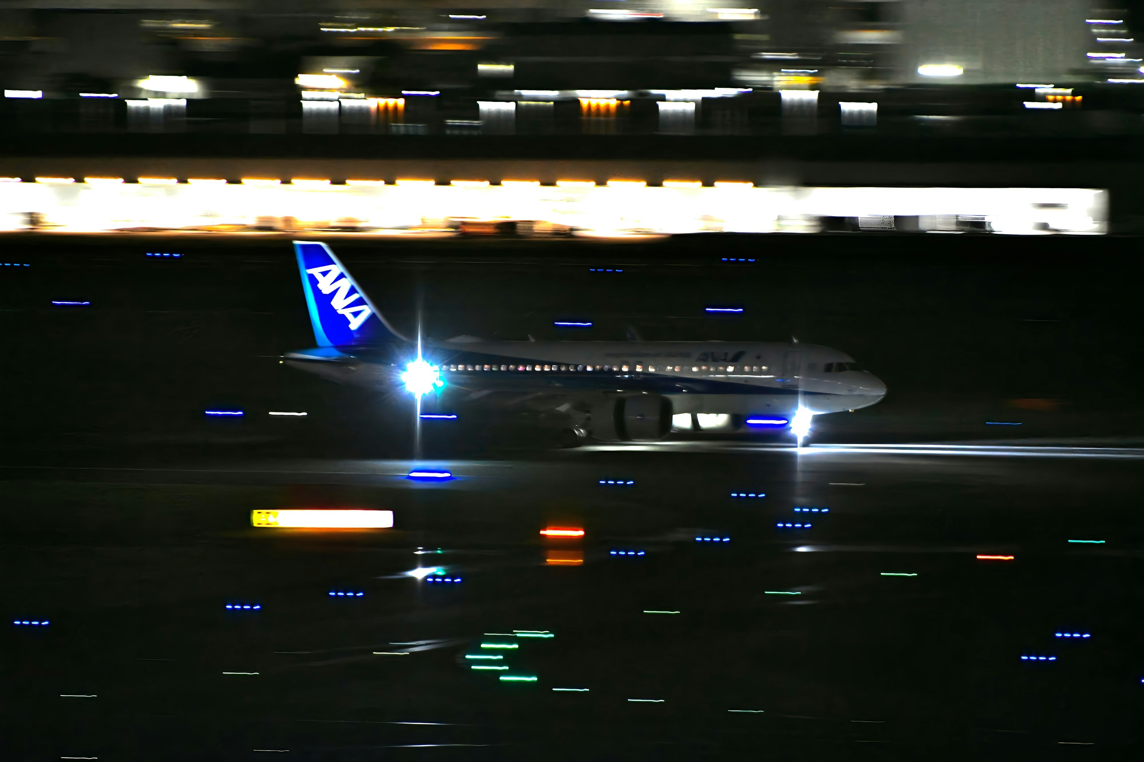 Avión de ANA aterrizando de noche con pista iluminada