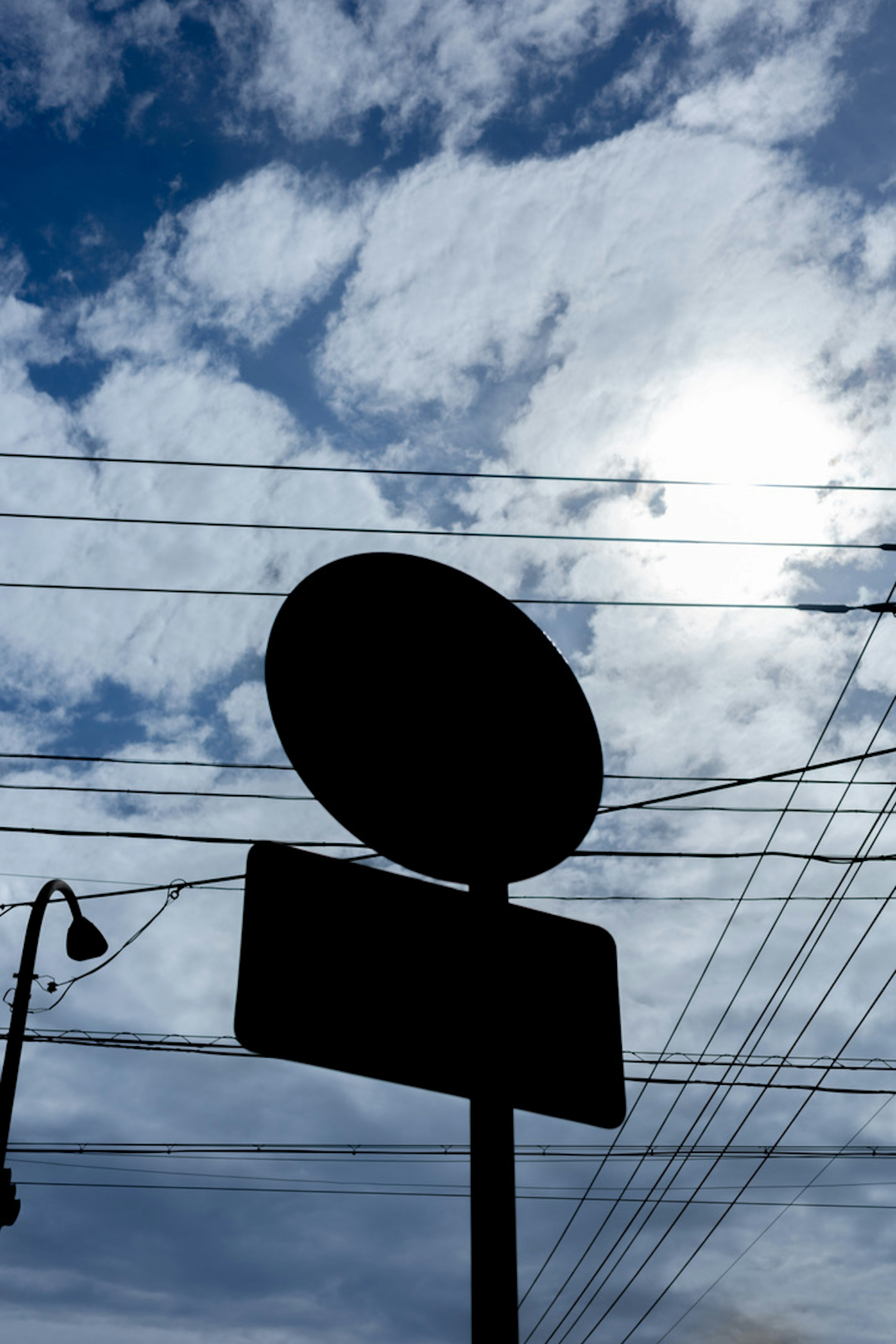 Silhouette eines Schildes vor einem Hintergrund aus Wolken und Stromleitungen