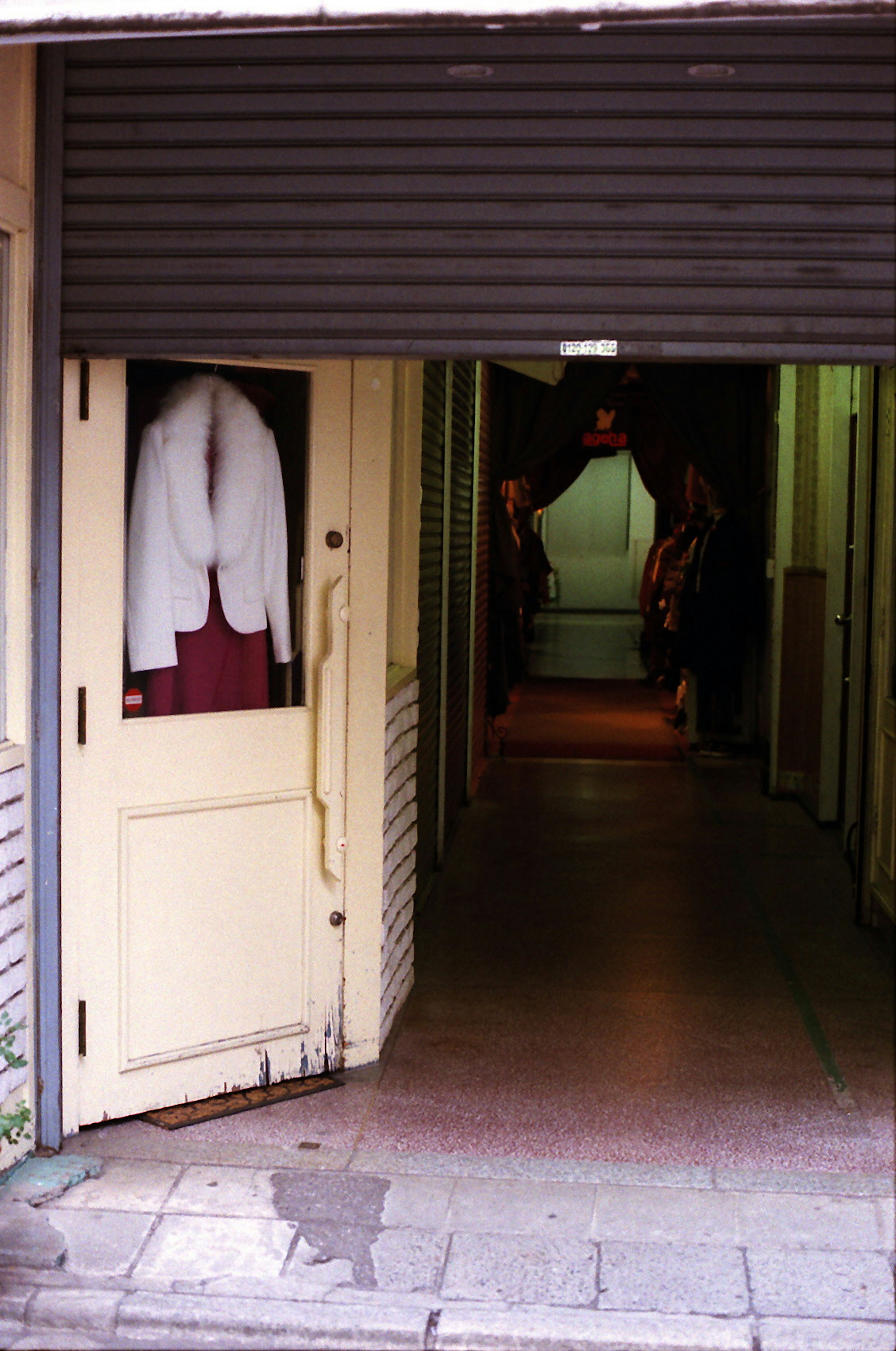 Entrance with a white coat hanging on the door and a dimly lit corridor