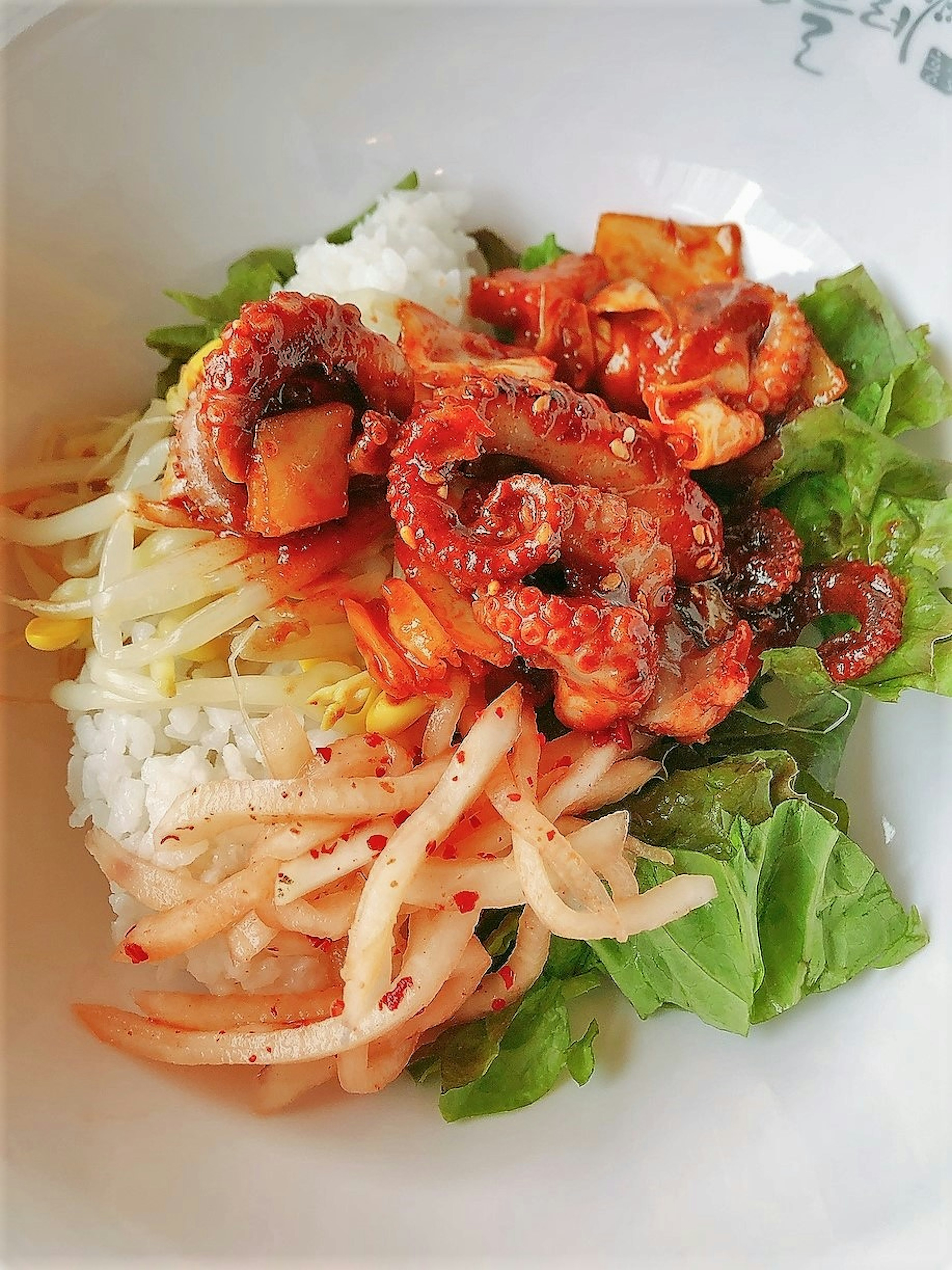 A dish featuring octopus served on rice with fresh vegetables