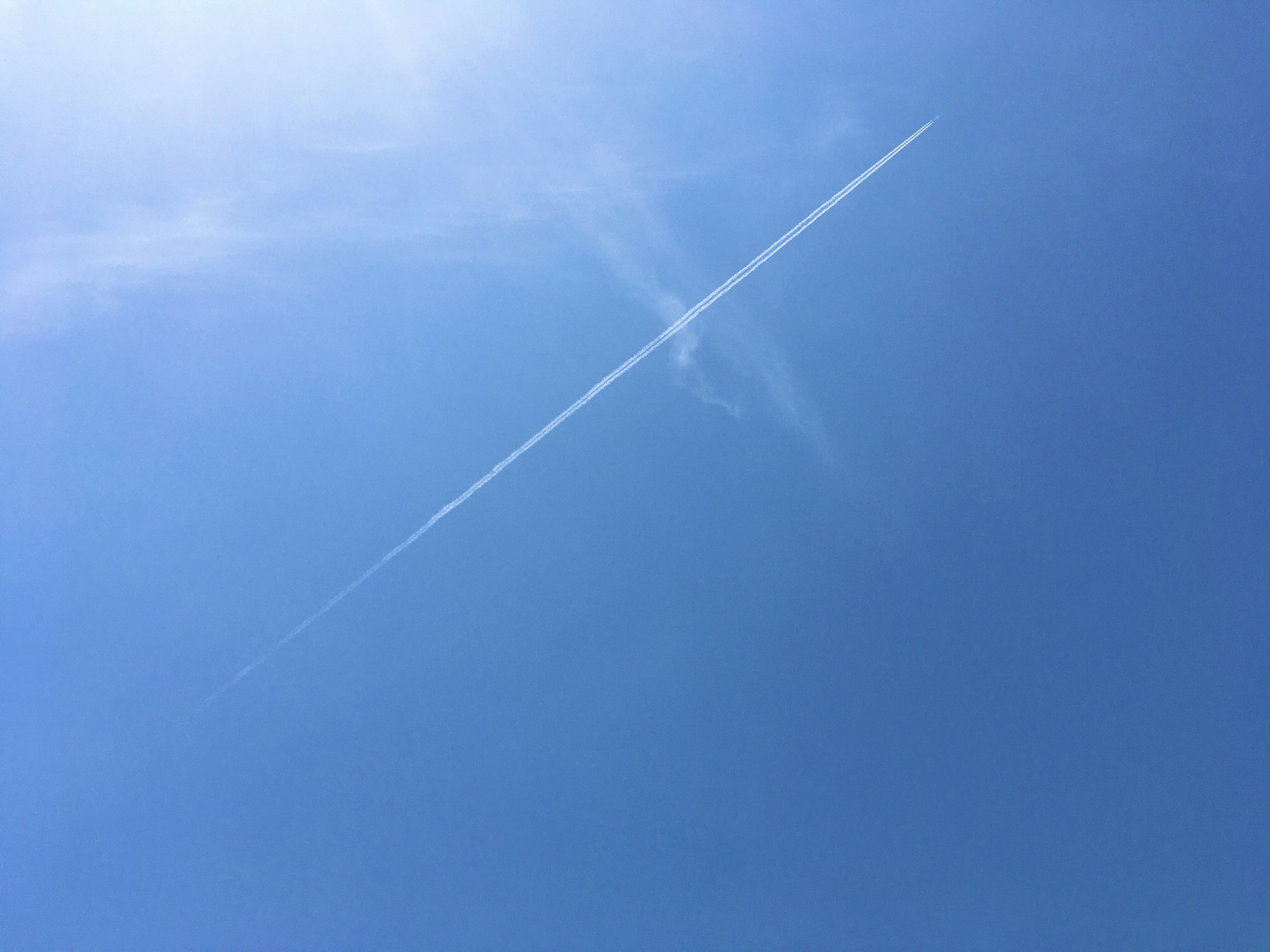 Contrail streak across a clear blue sky