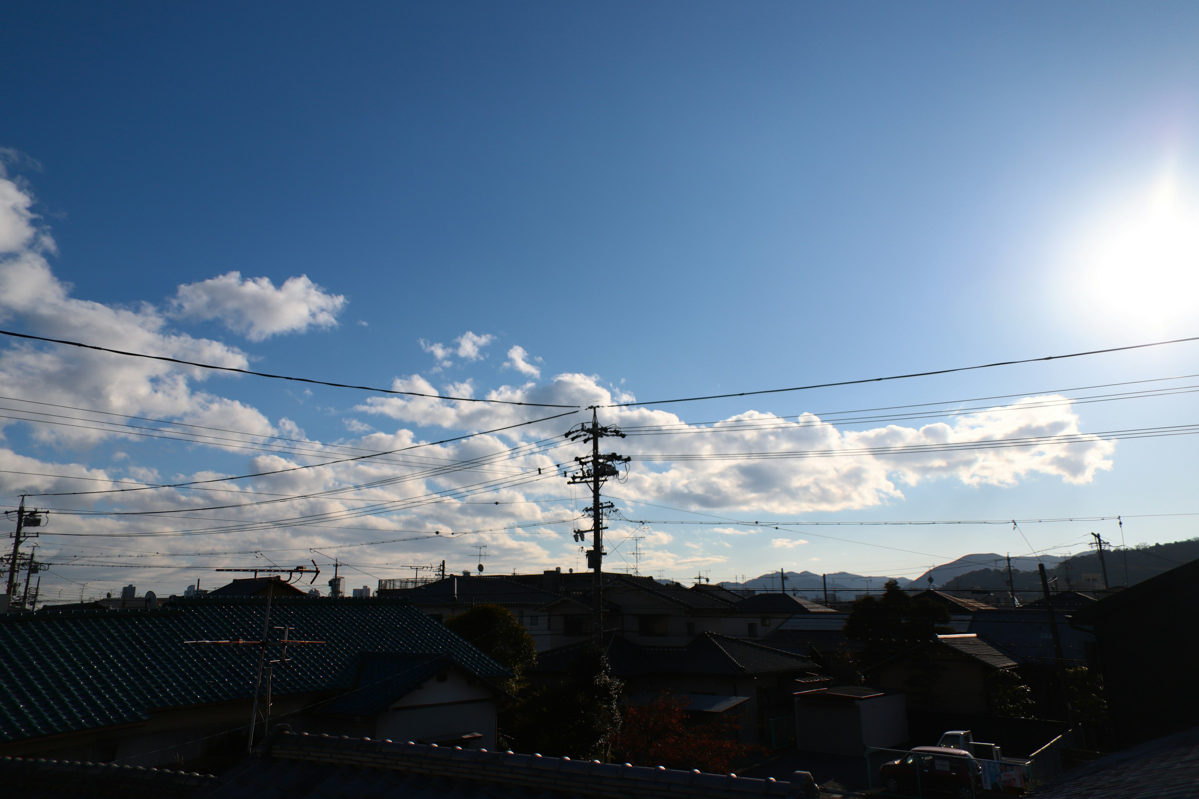 Clear blue sky with white clouds mountains and utility pole in the distance