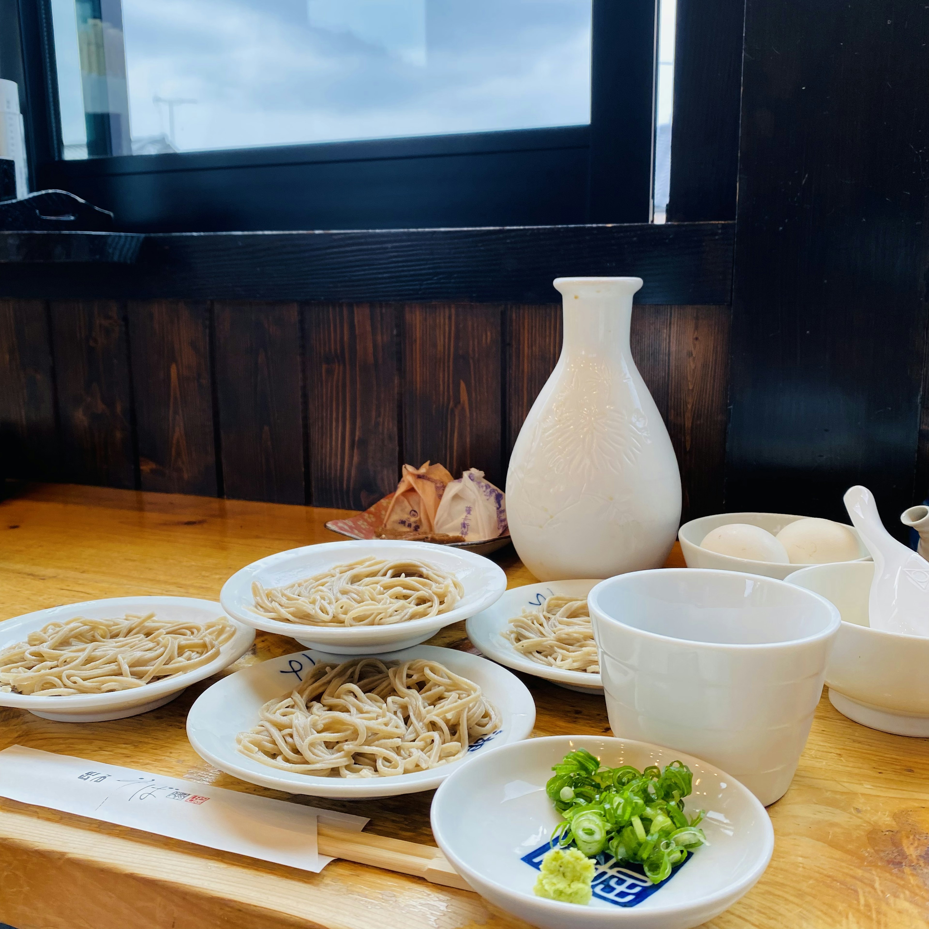 Une scène de repas japonais traditionnel avec des assiettes de soba et des oignons verts