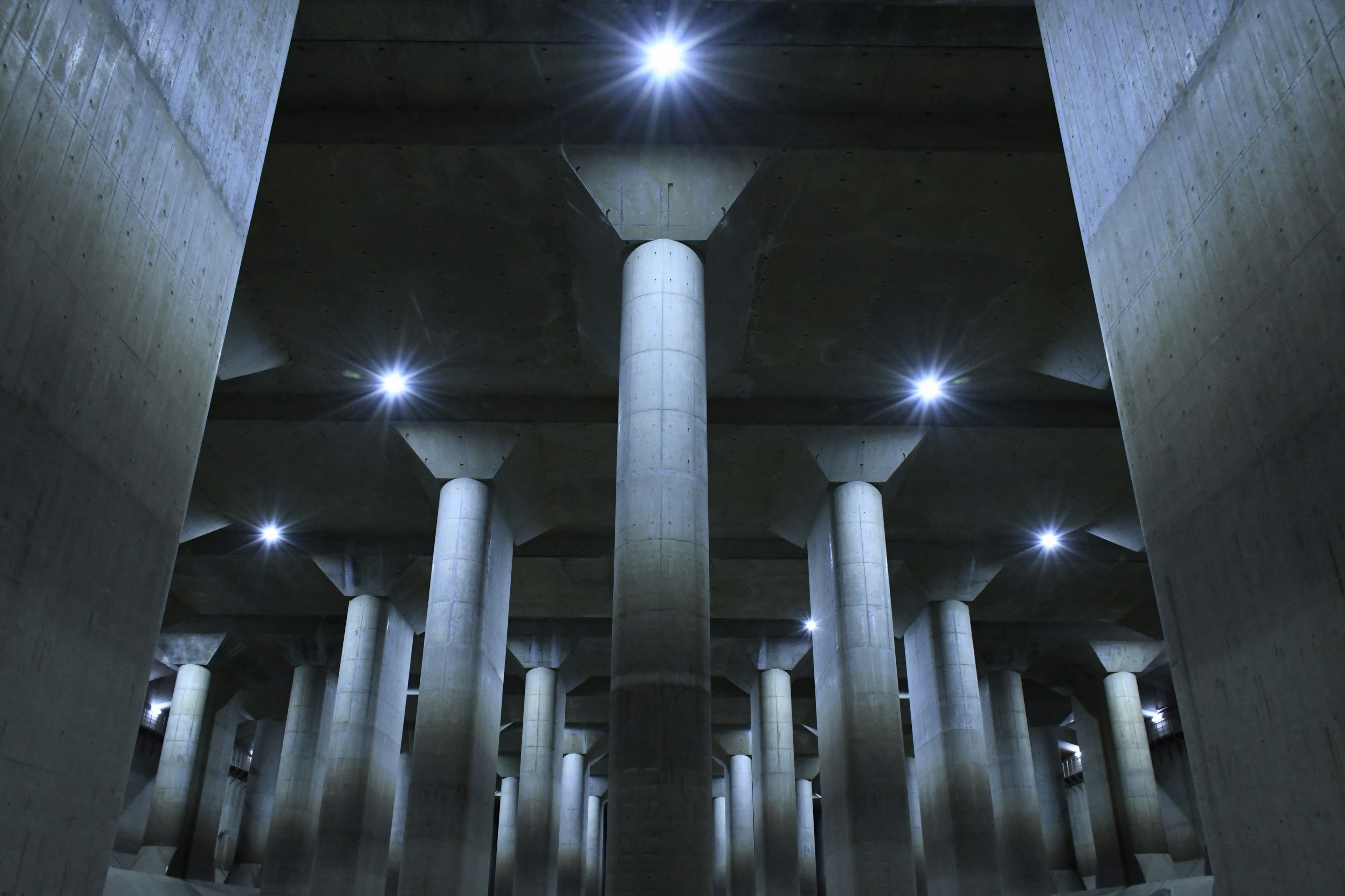 A space featuring concrete pillars and bright lighting underground