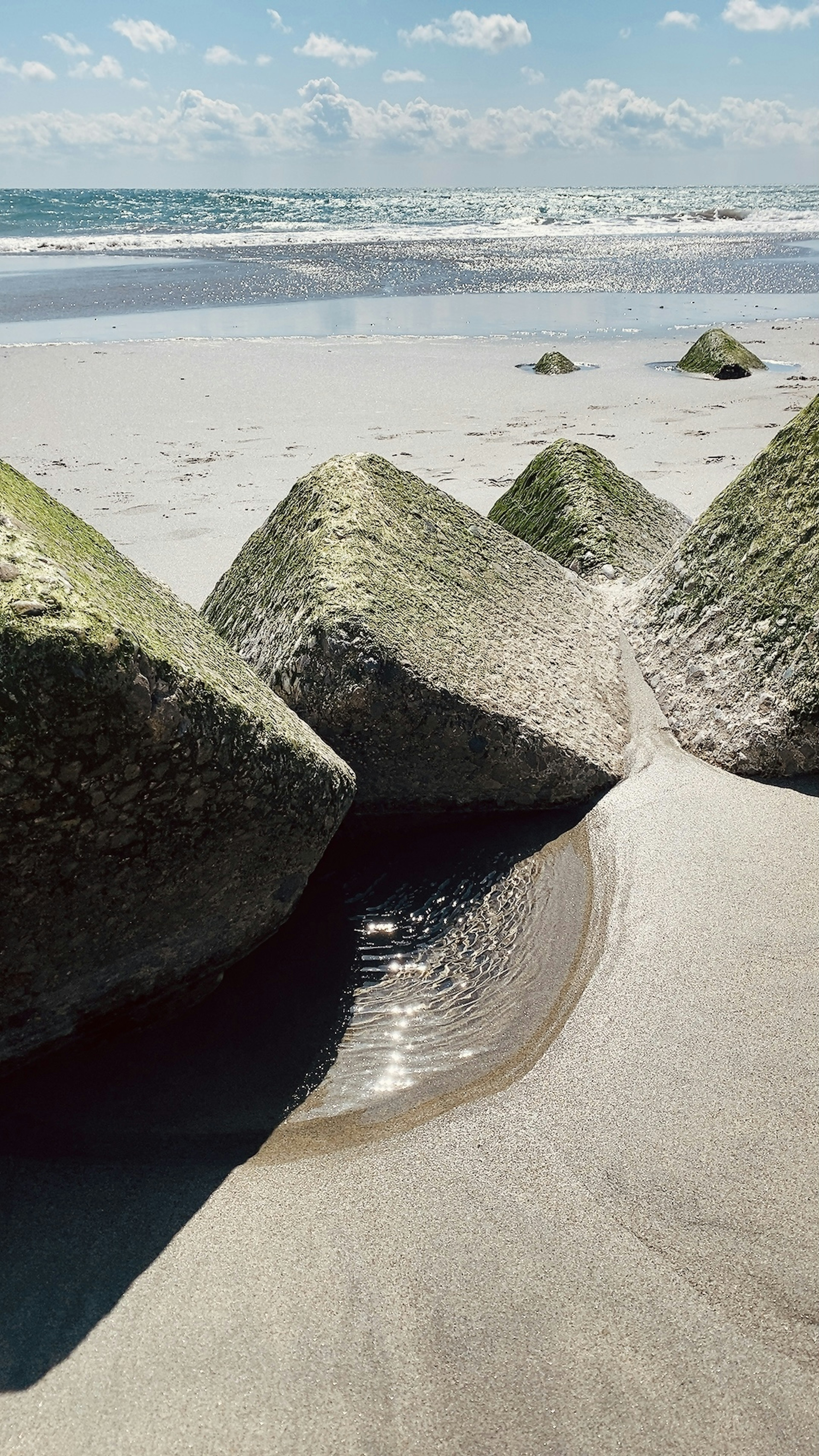 Grandes rocas en una playa de arena con olas del océano