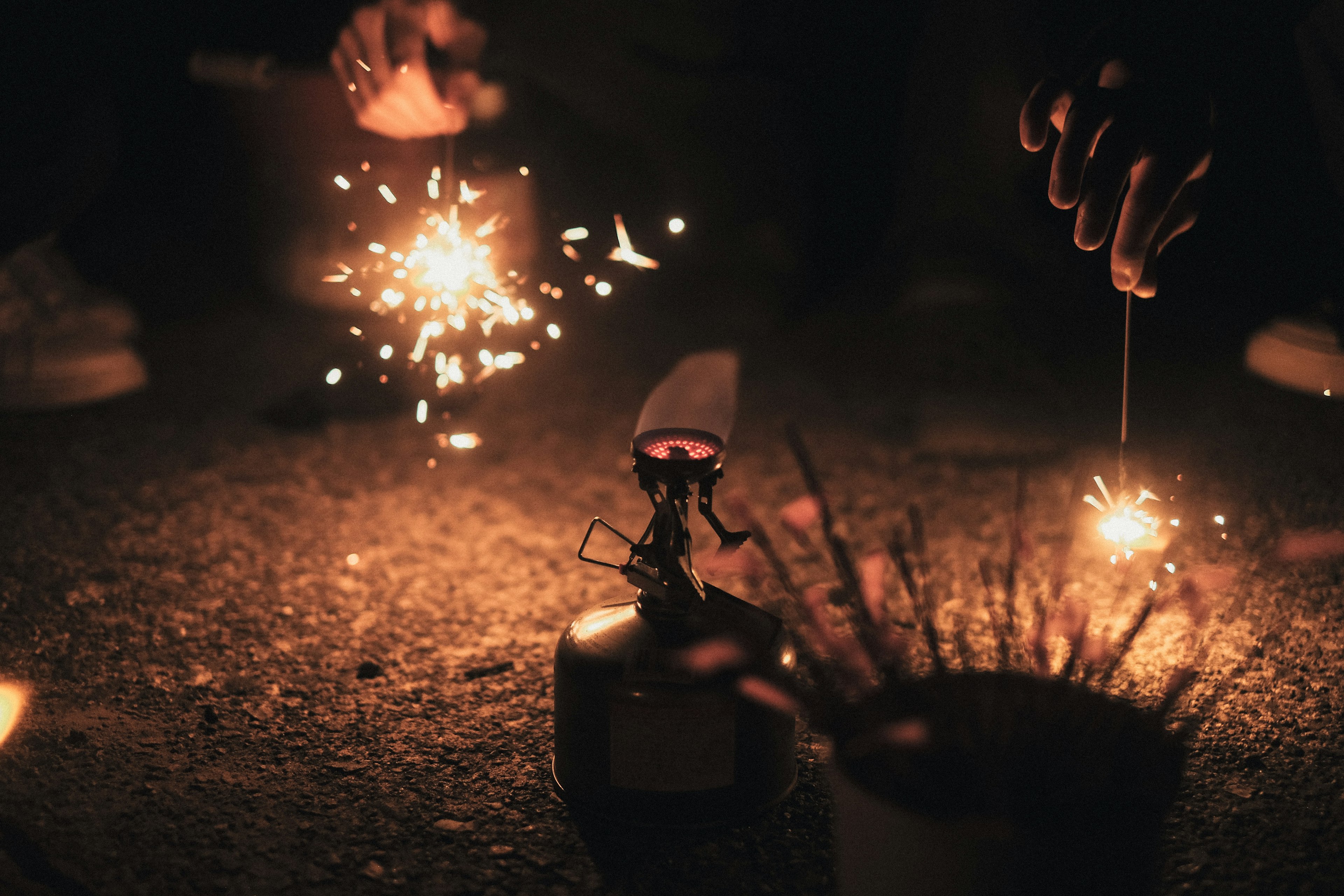 Hands holding sparklers and firecrackers in a dark setting