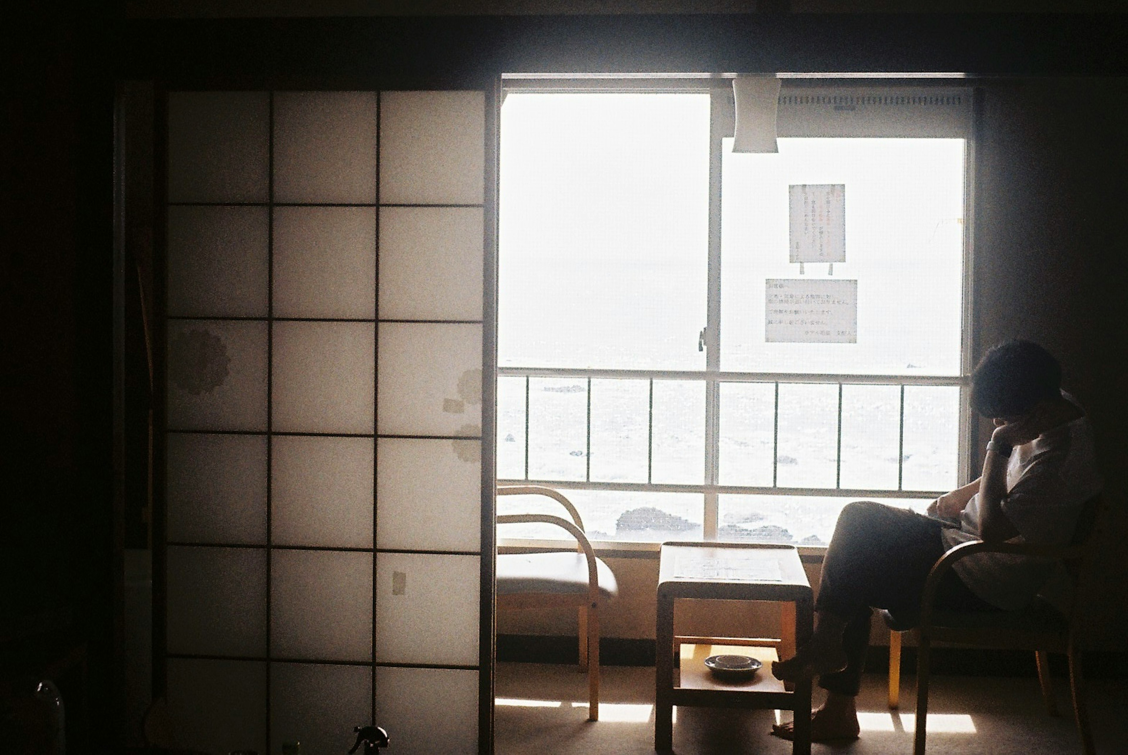 A person sitting by the window in a room with shoji screens