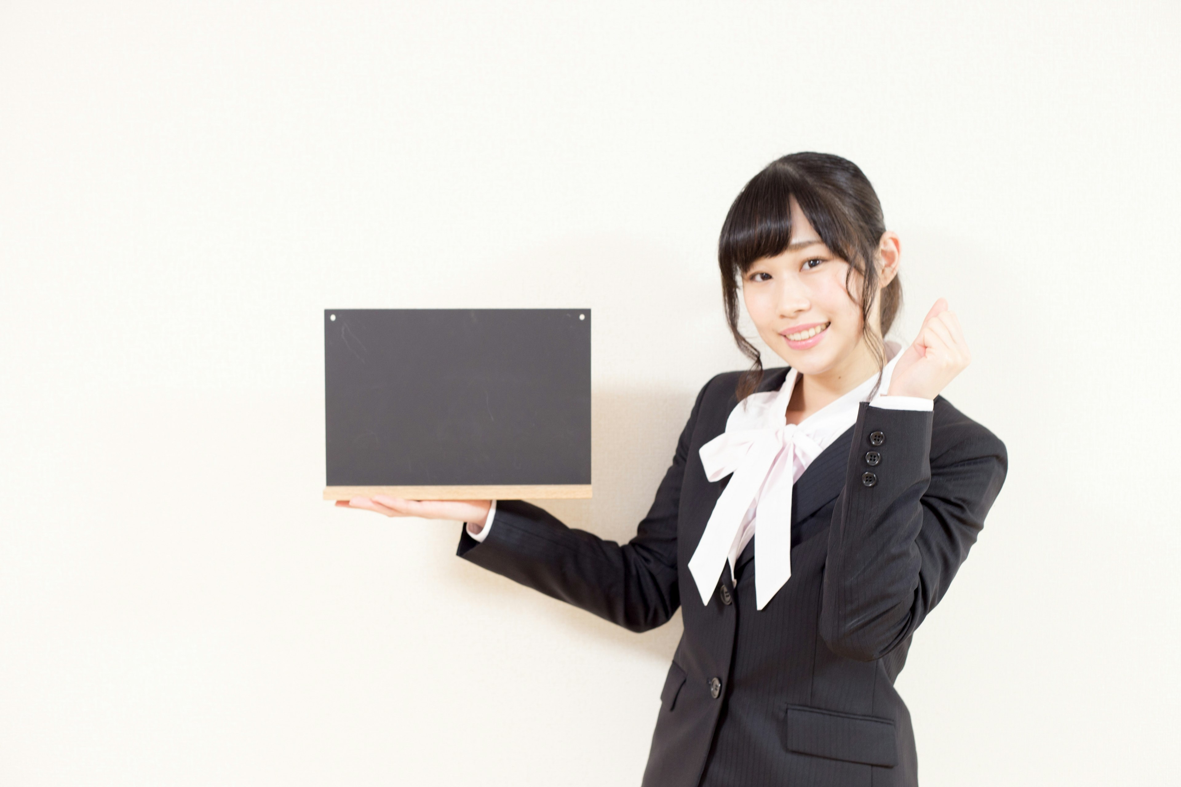 Young woman smiling and making a peace sign while holding a black board