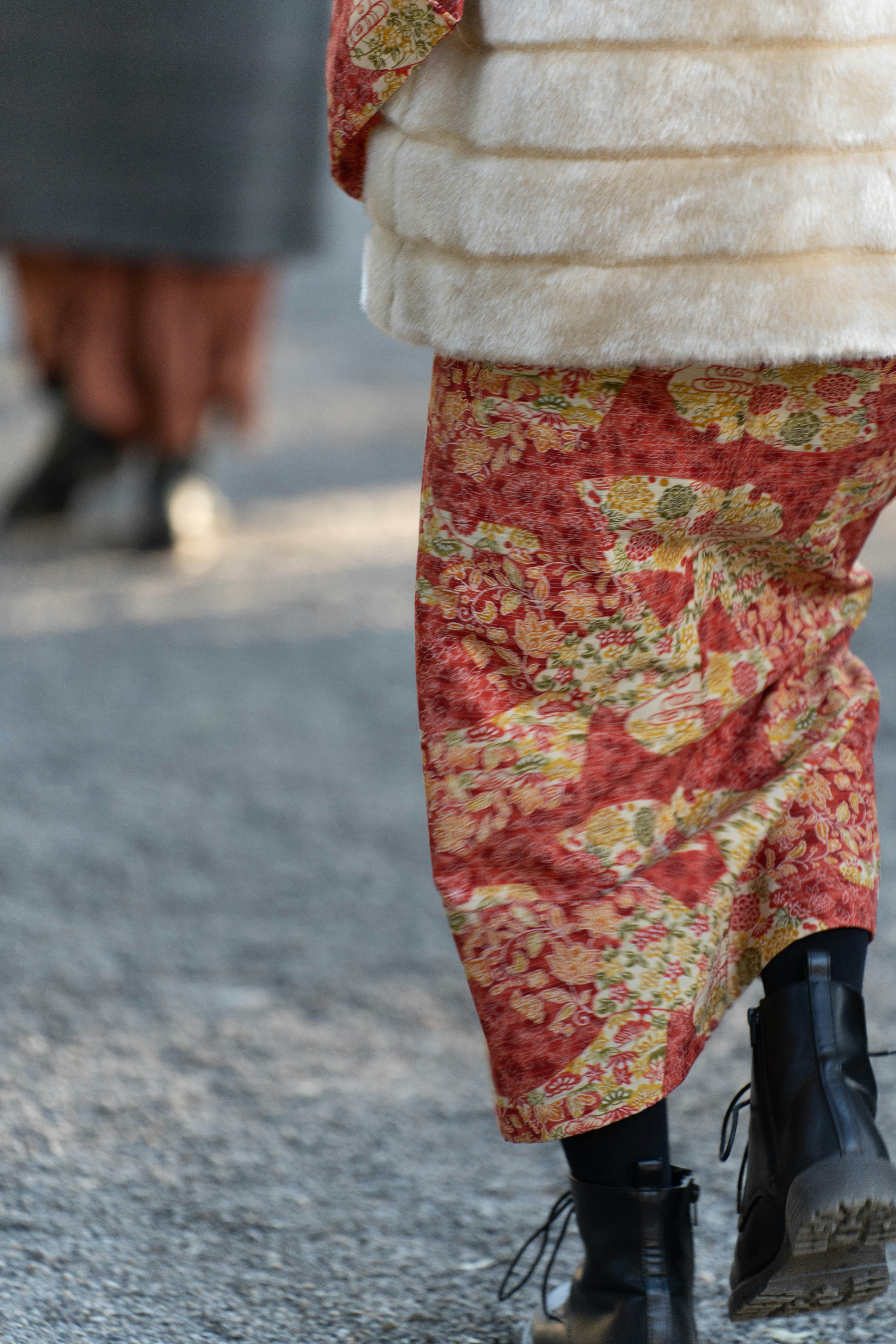 Person wearing floral patterned pants in red and yellow walking on a path