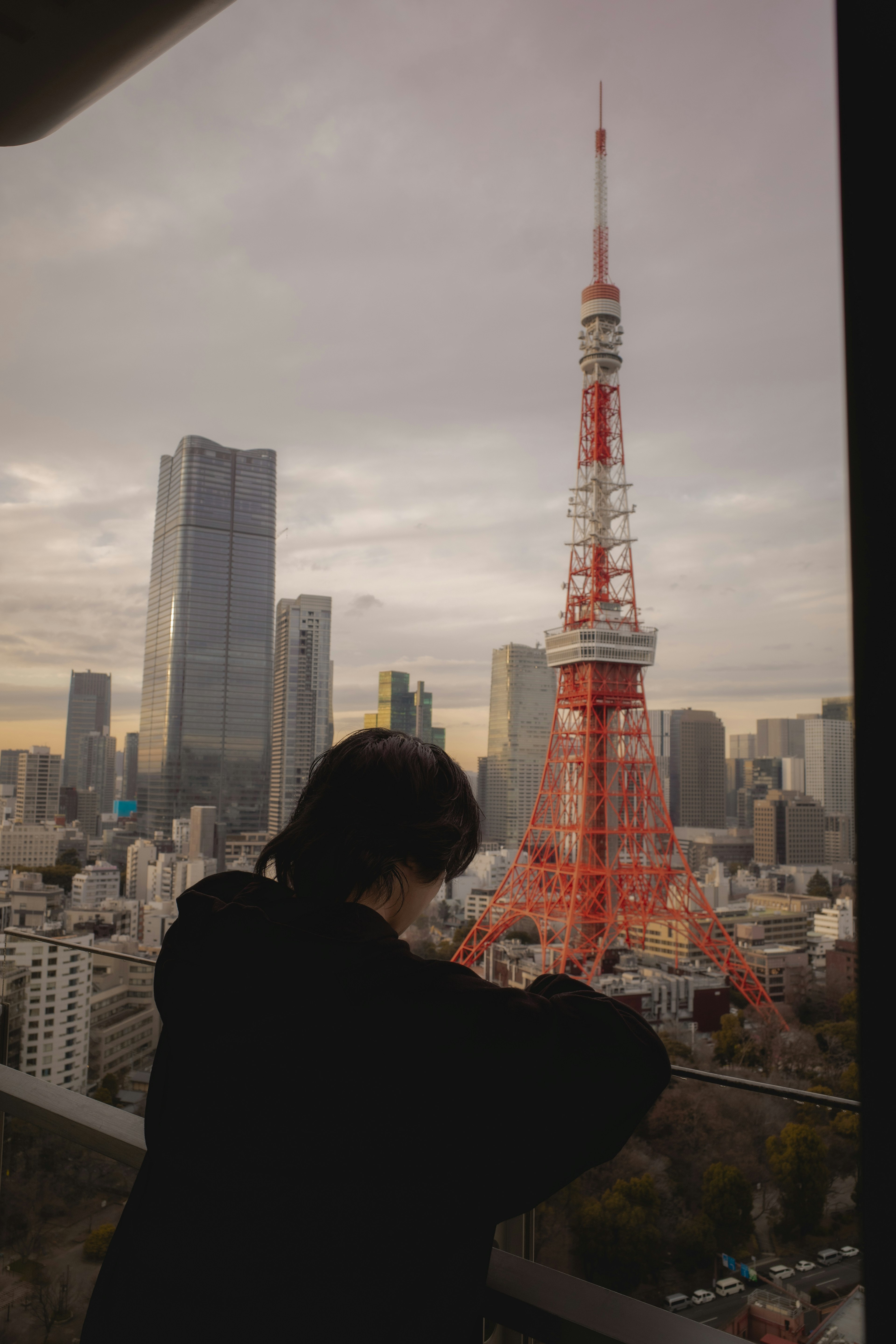 Siluet seorang wanita dengan Menara Tokyo di latar belakang melawan langit kota