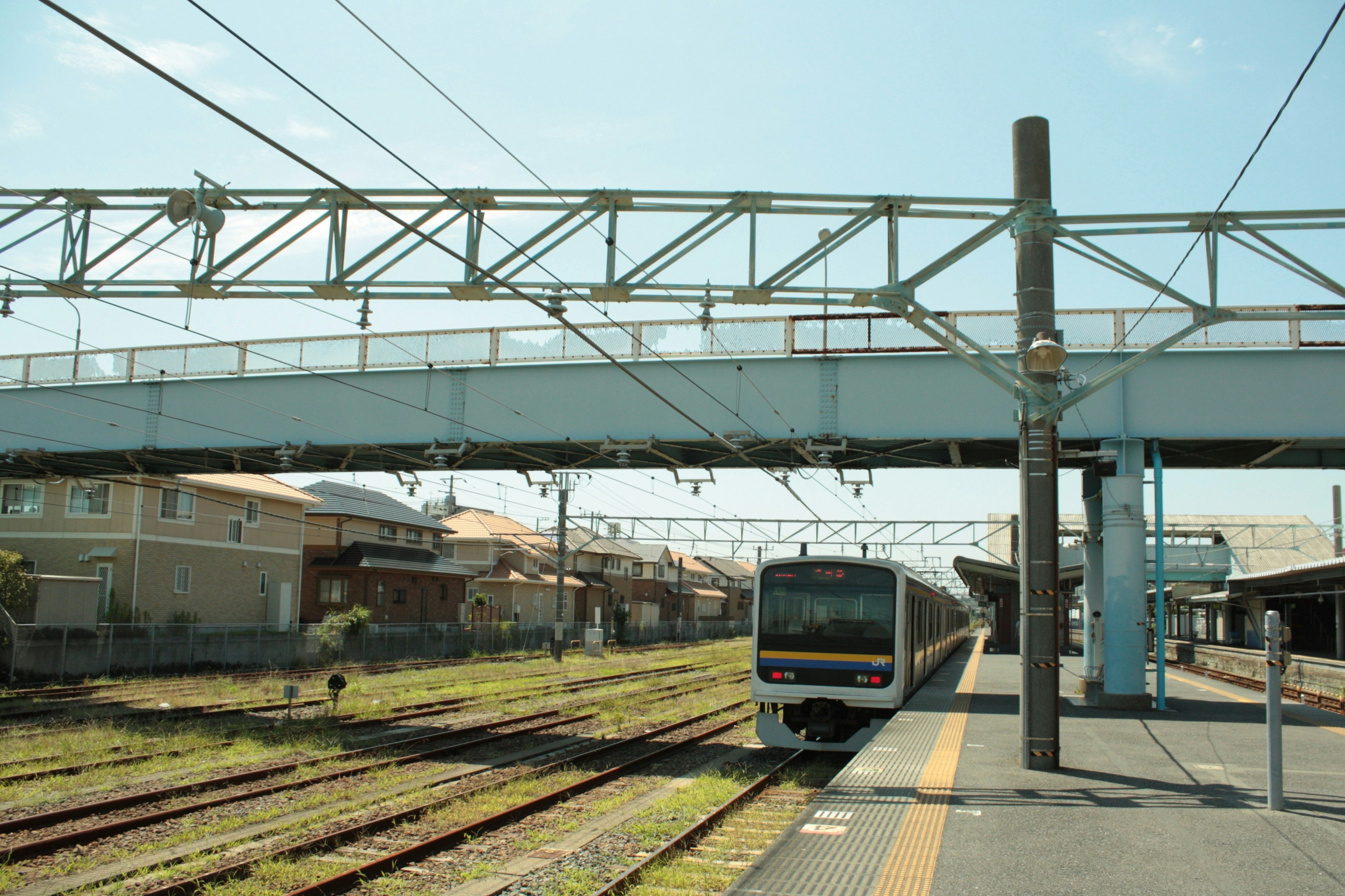 Scena di stazione ferroviaria con un treno in piattaforma cielo blu e edifici residenziali sullo sfondo