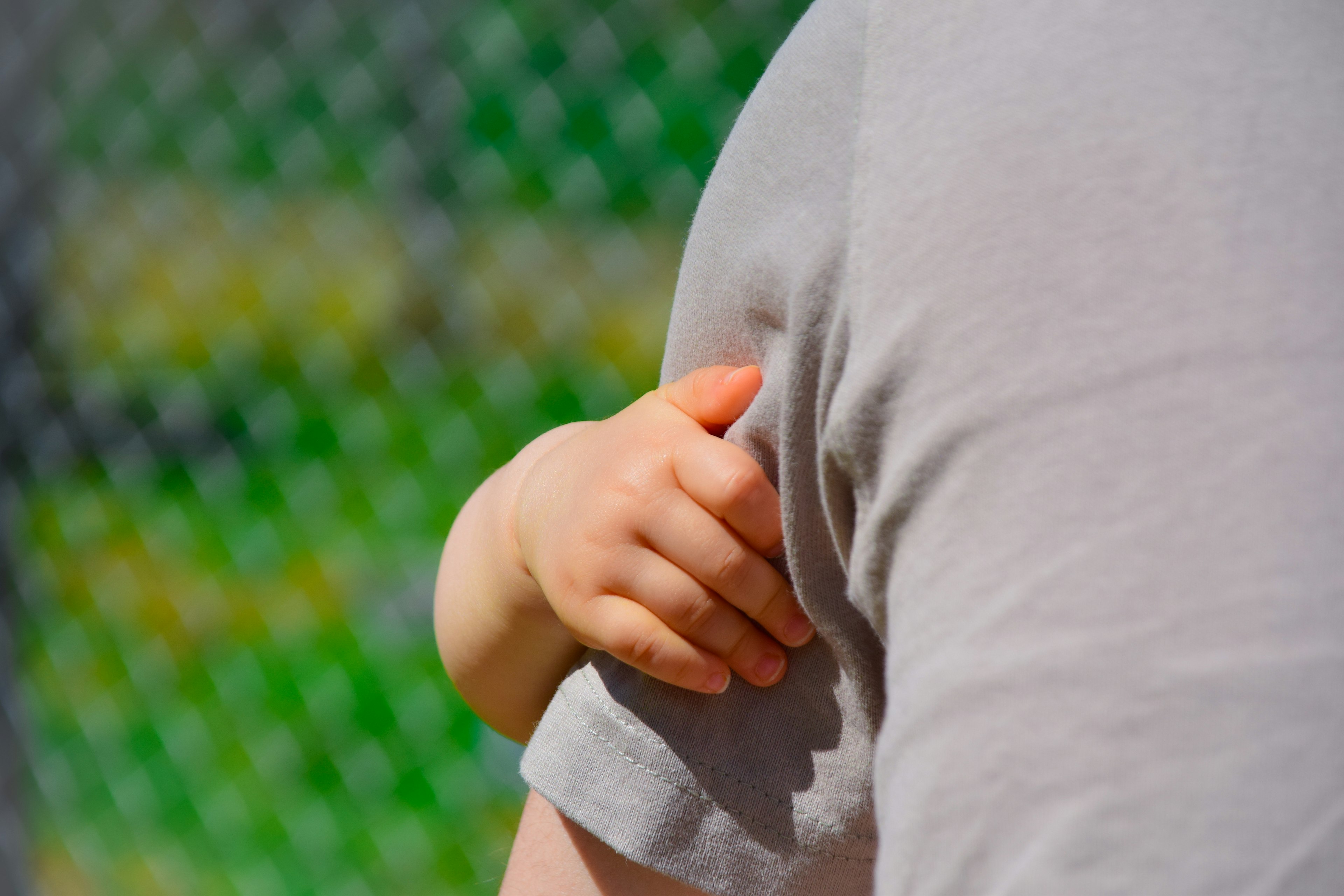 A child's hand gripping an adult's shirt in a close-up shot