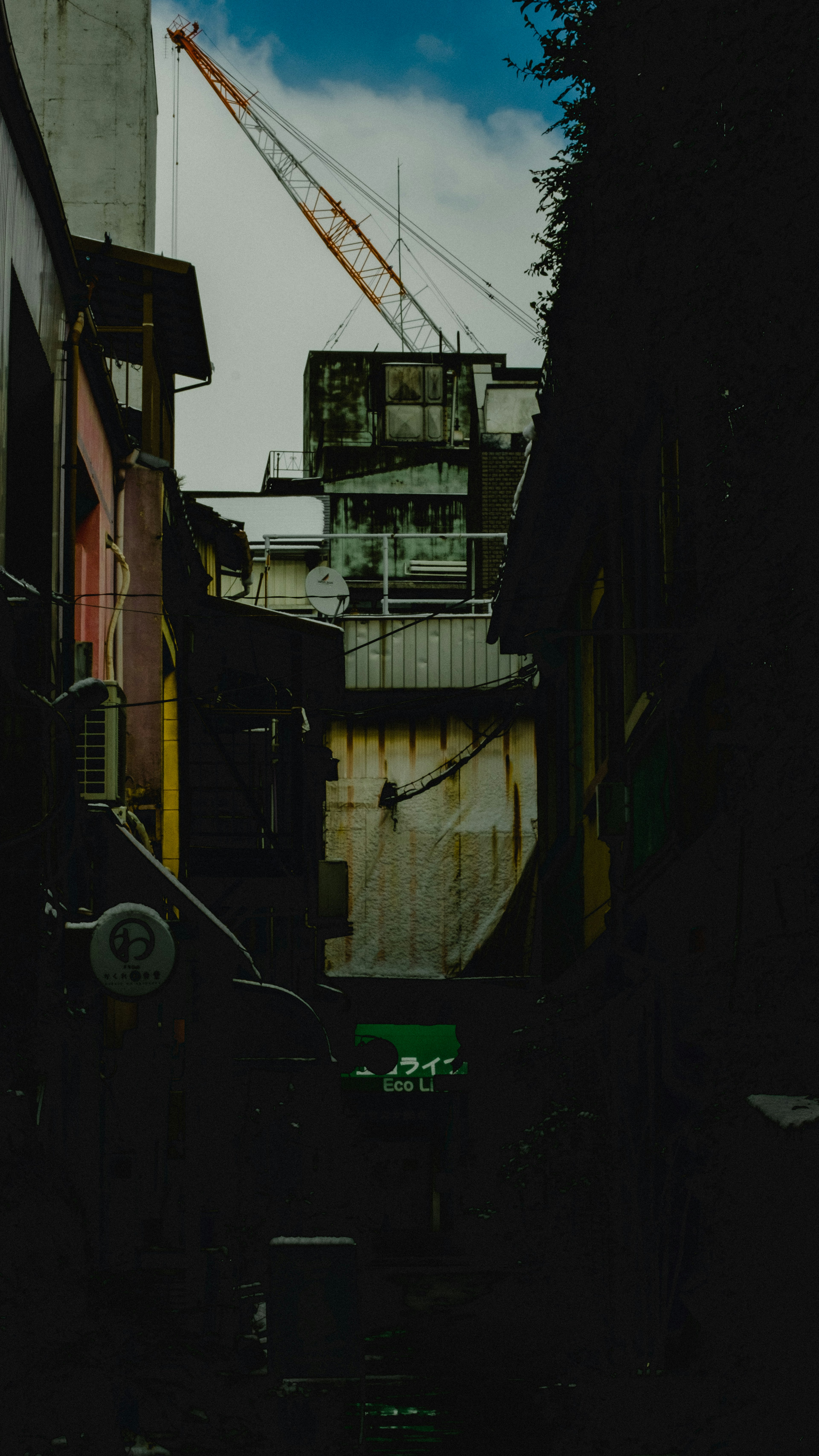 Callejón estrecho con edificios a ambos lados y una grúa visible arriba