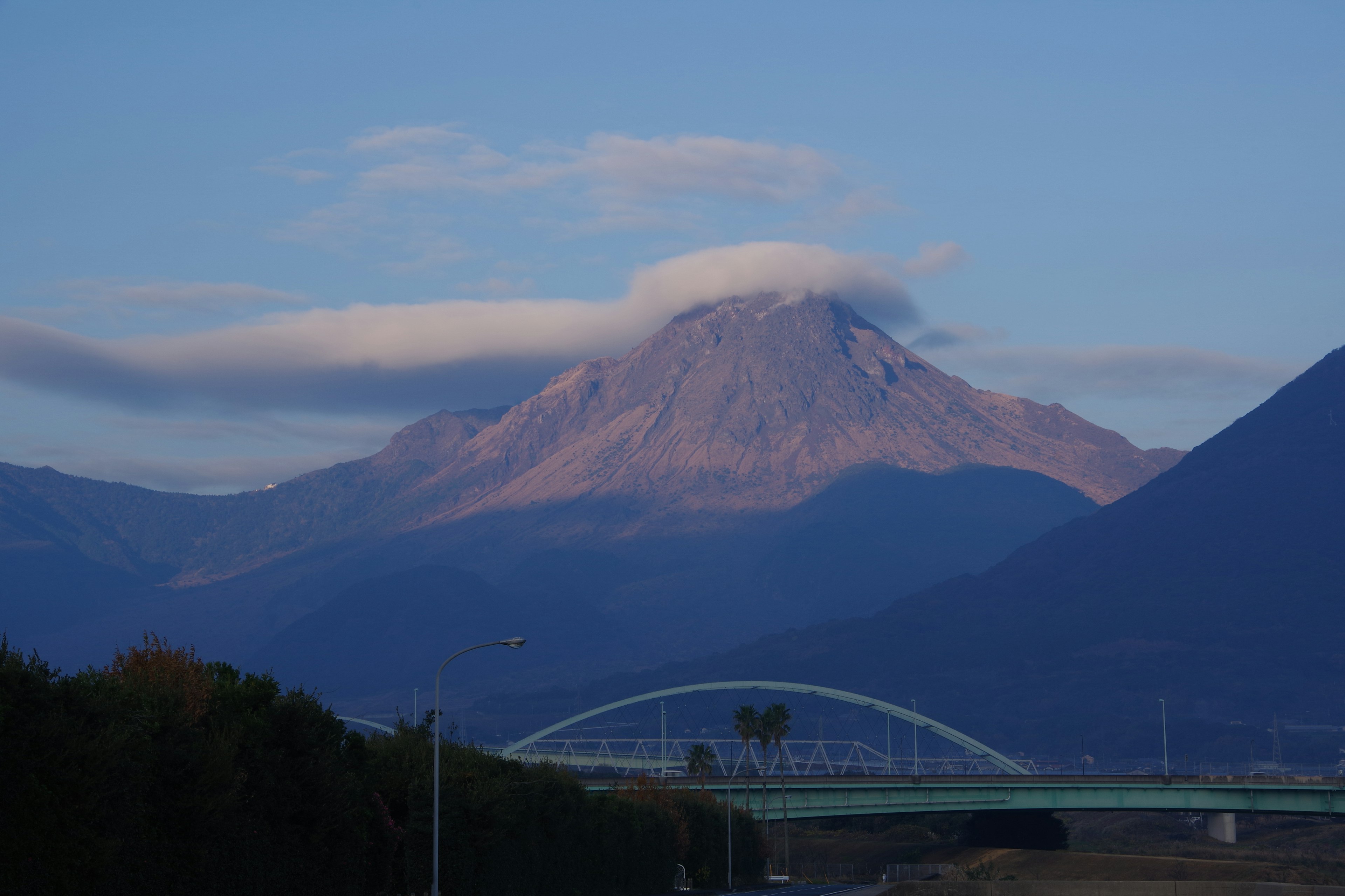 Vista escénica de una montaña con nubes y un puente